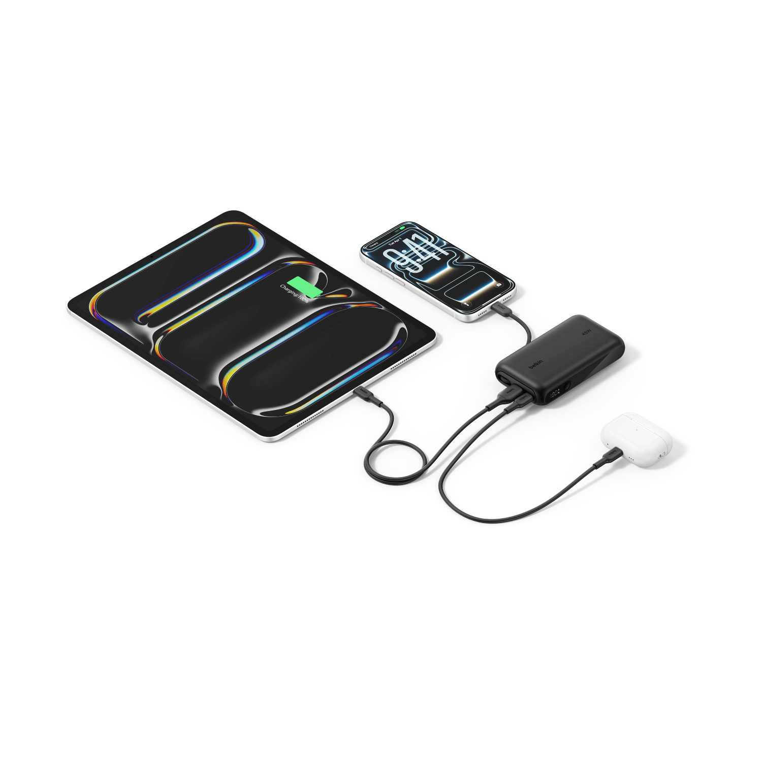 Una batería portátil negra carga una tableta, un smartphone y auriculares blancos con cables USB-C sobre fondo blanco.