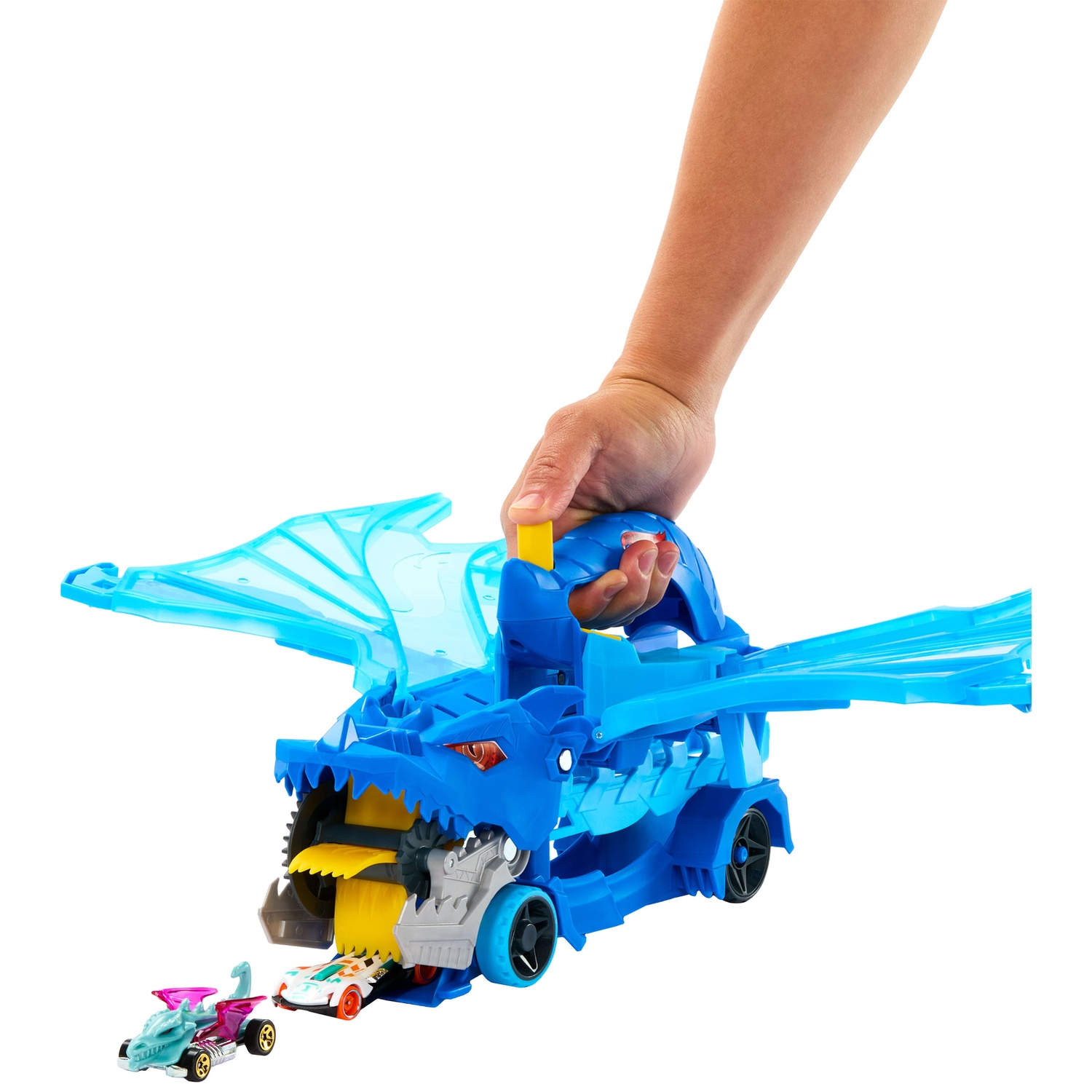 A hand holds a blue dragon toy car transporter that swallows cars, with a car in front.