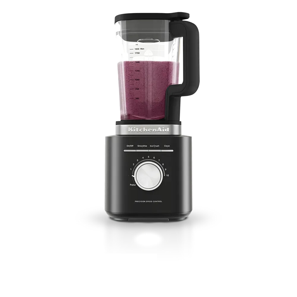 Ein schwarzer KitchenAid Standmixer mit einem Krug voller lila Smoothie und einem großen Drehregler auf einer weißen Fläche.