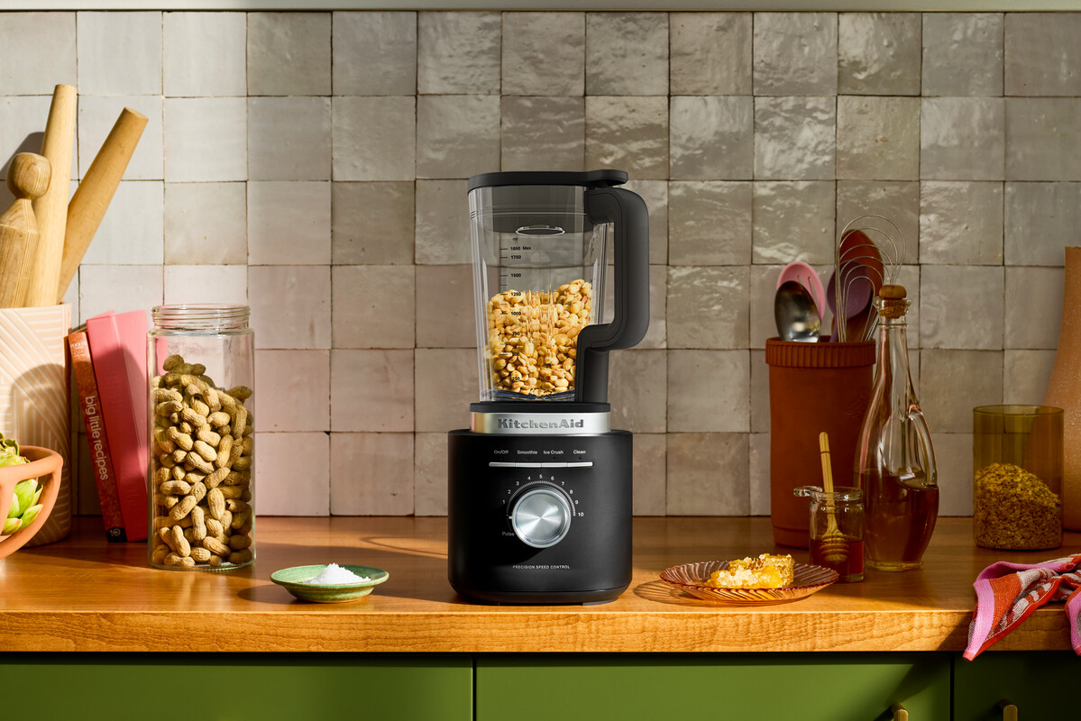Ein schwarzer KitchenAid-Mixer mit Erdnüssen auf einer Holzküchenarbeitsplatte.