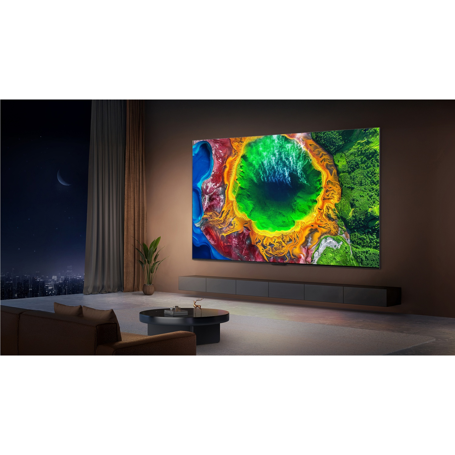 Soggiorno con grande TV che mostra paesaggio colorato, divano, tavolino e vista notturna della città dalla finestra.