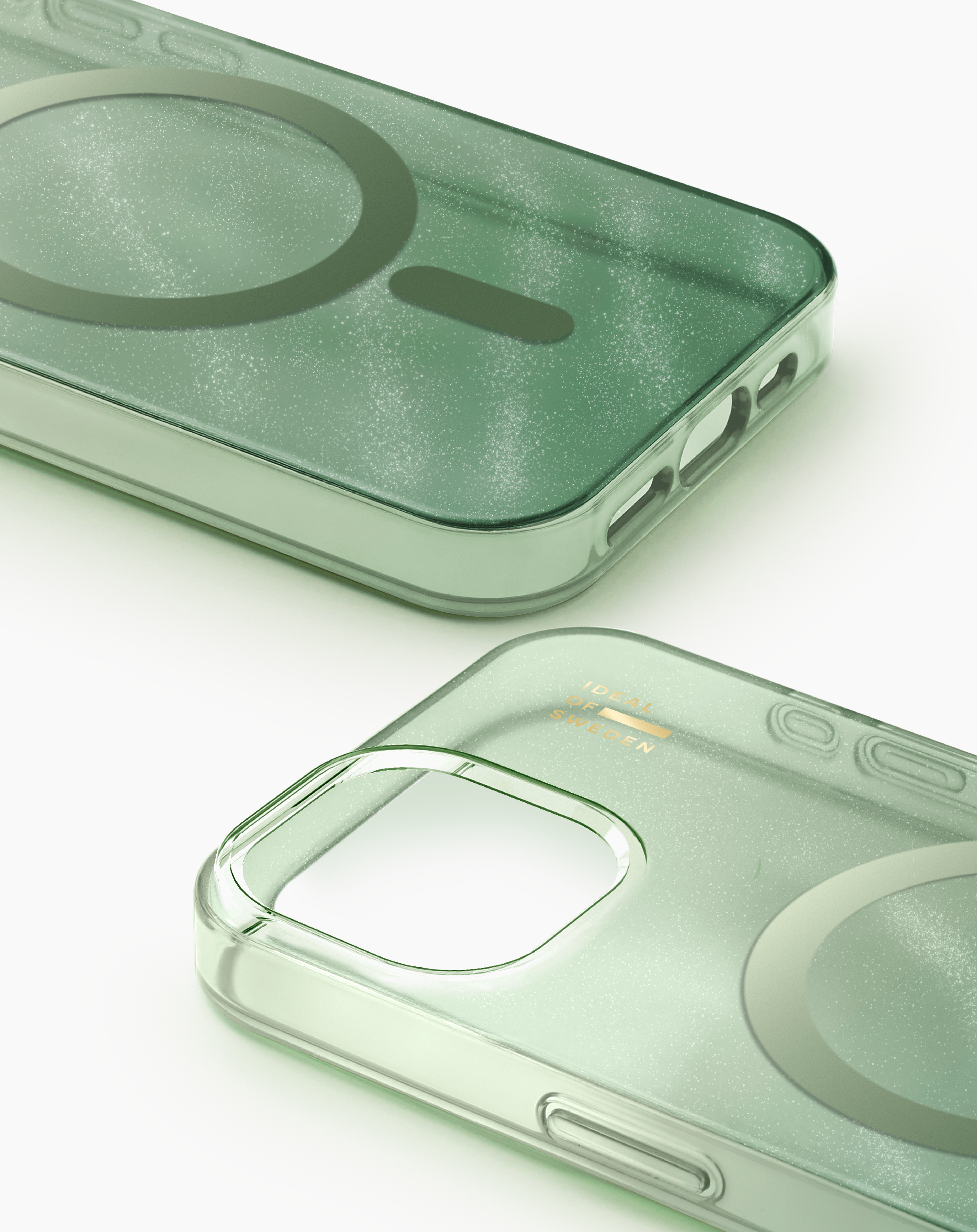 Zwei glitzernde, salbeigrüne Handyhüllen mit MagSafe-Ring und Markenlogo auf weißem Grund.