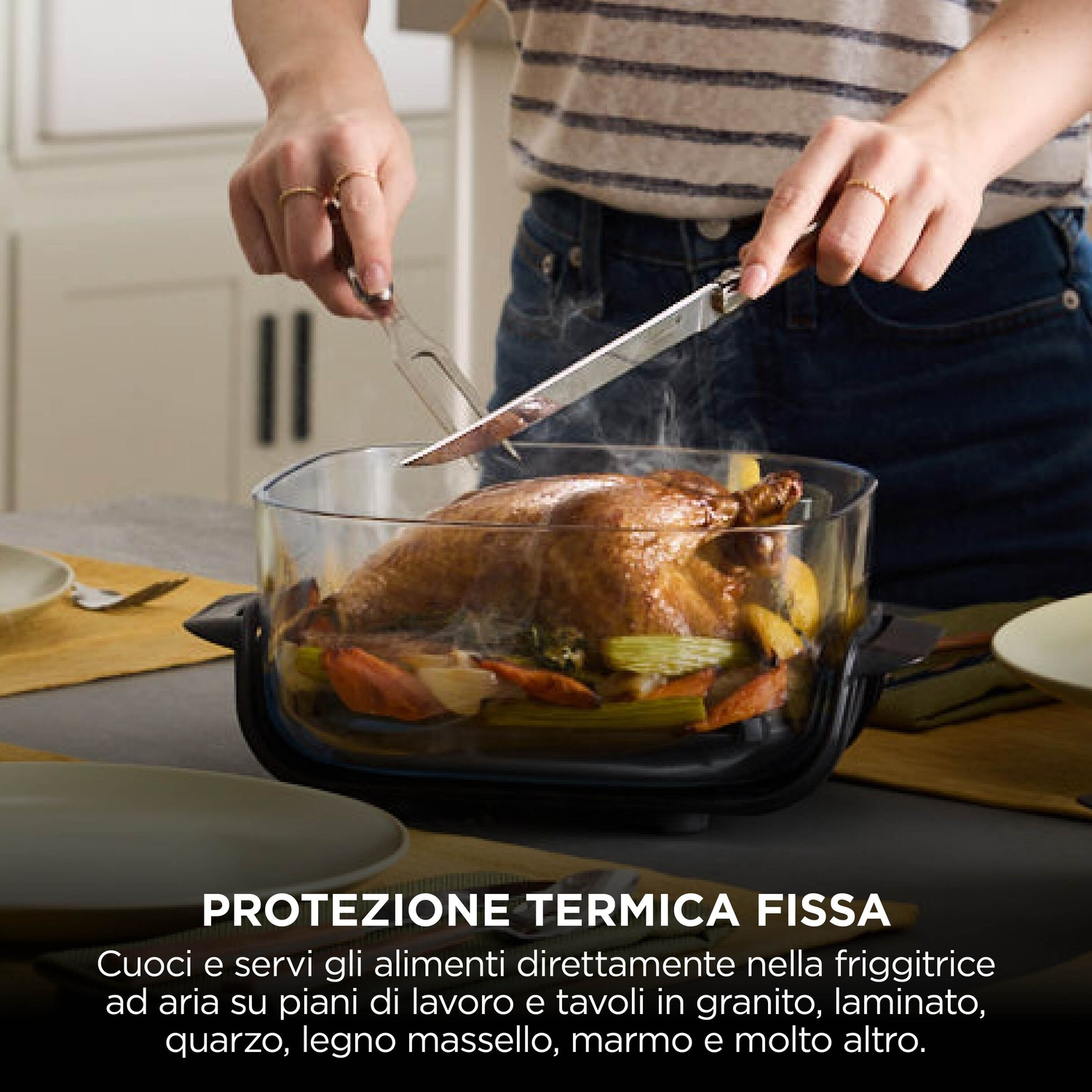 Persona che taglia un pollo arrosto intero in una friggitrice ad aria in vetro.