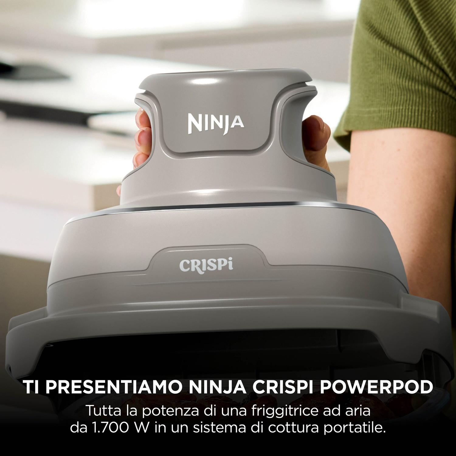 Una persona tiene in mano un elettrodomestico da cucina grigio Ninja Crispi Powerpod.