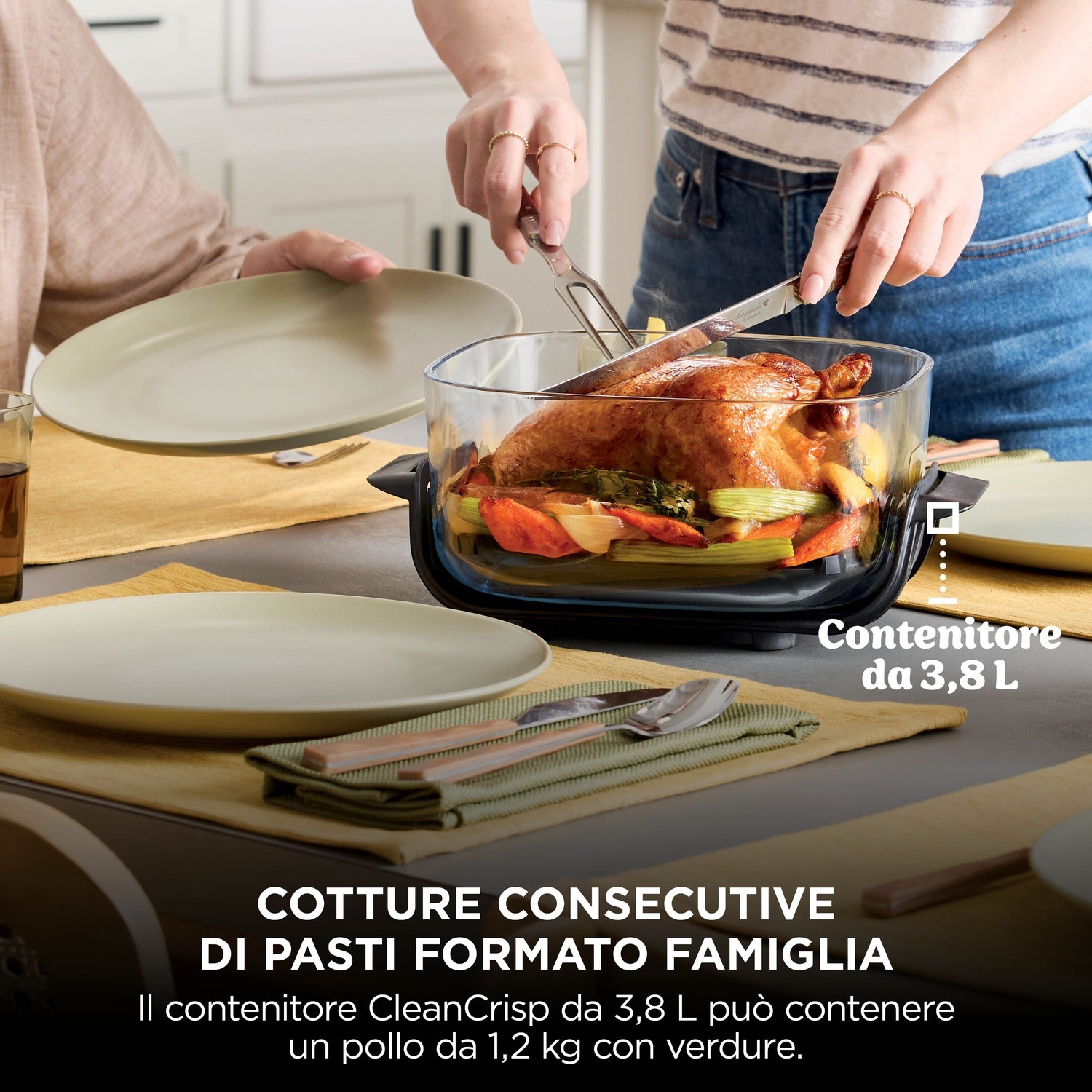 Persone tagliano un pollo arrosto con verdure in una pirofila di vetro a tavola.
