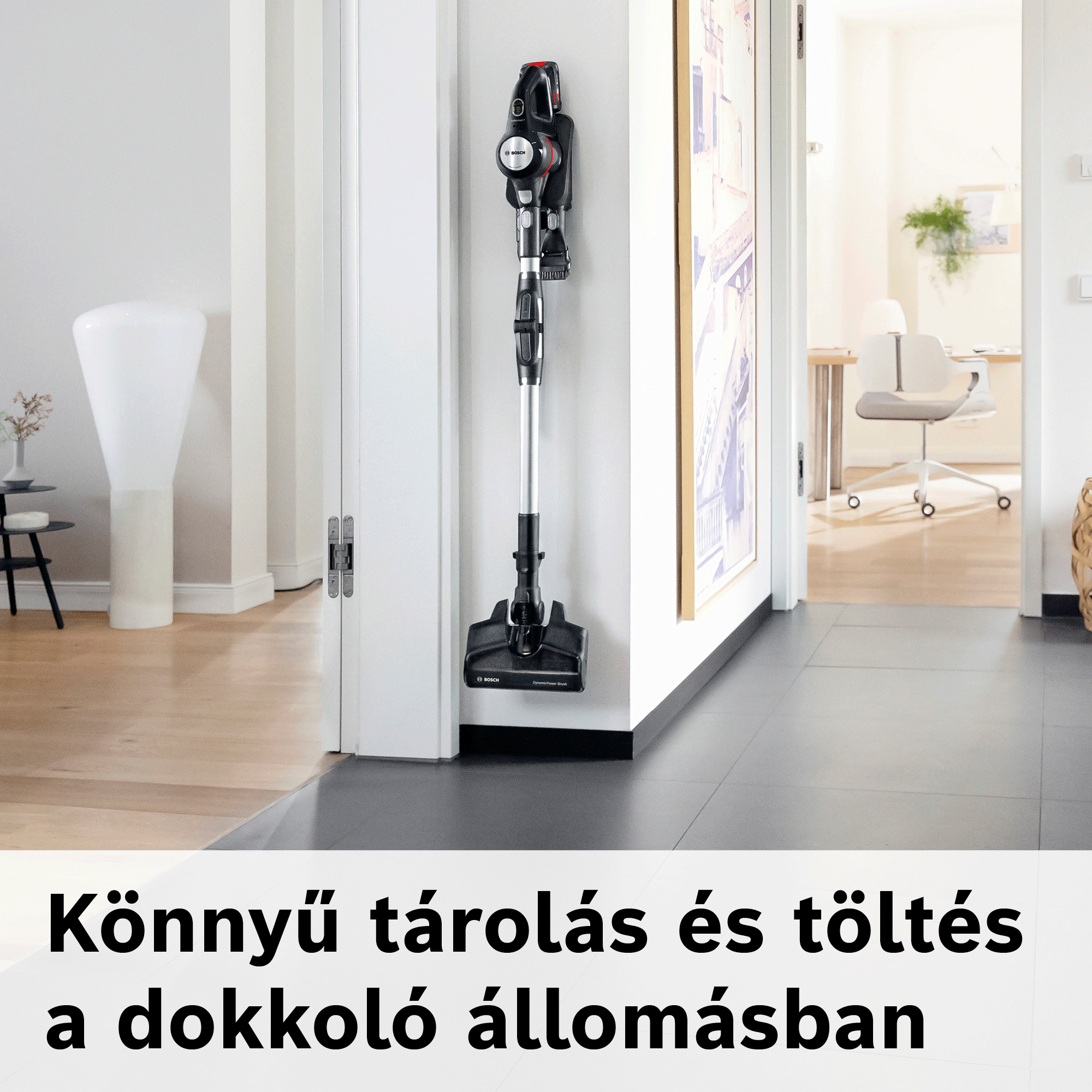 Egy fekete Bosch porszívó lóg a dokkolóállomáson egy fehér folyosói falon.