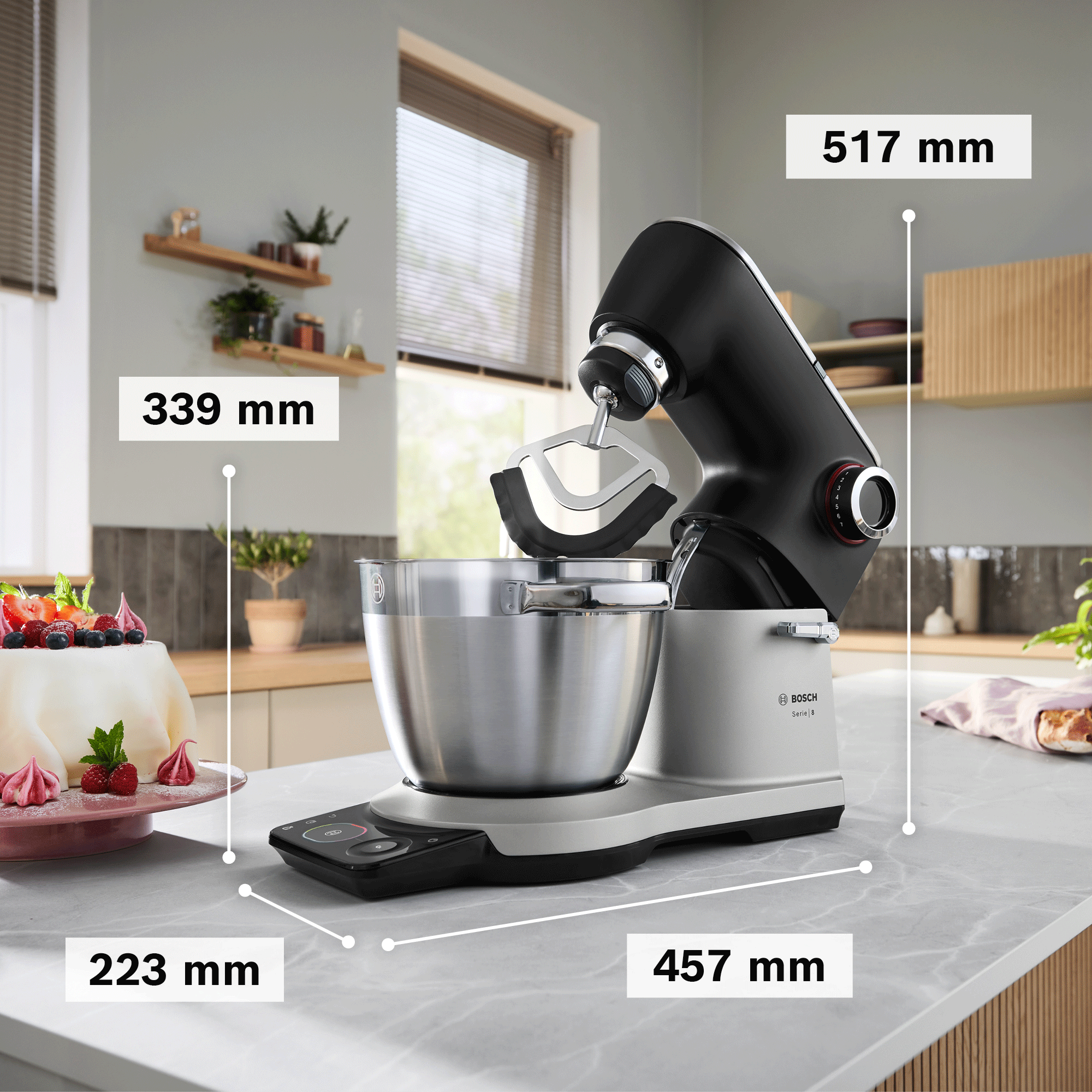 Fekete és ezüst Bosch konyhai robotgép egy konyhapulton, méretekkel.