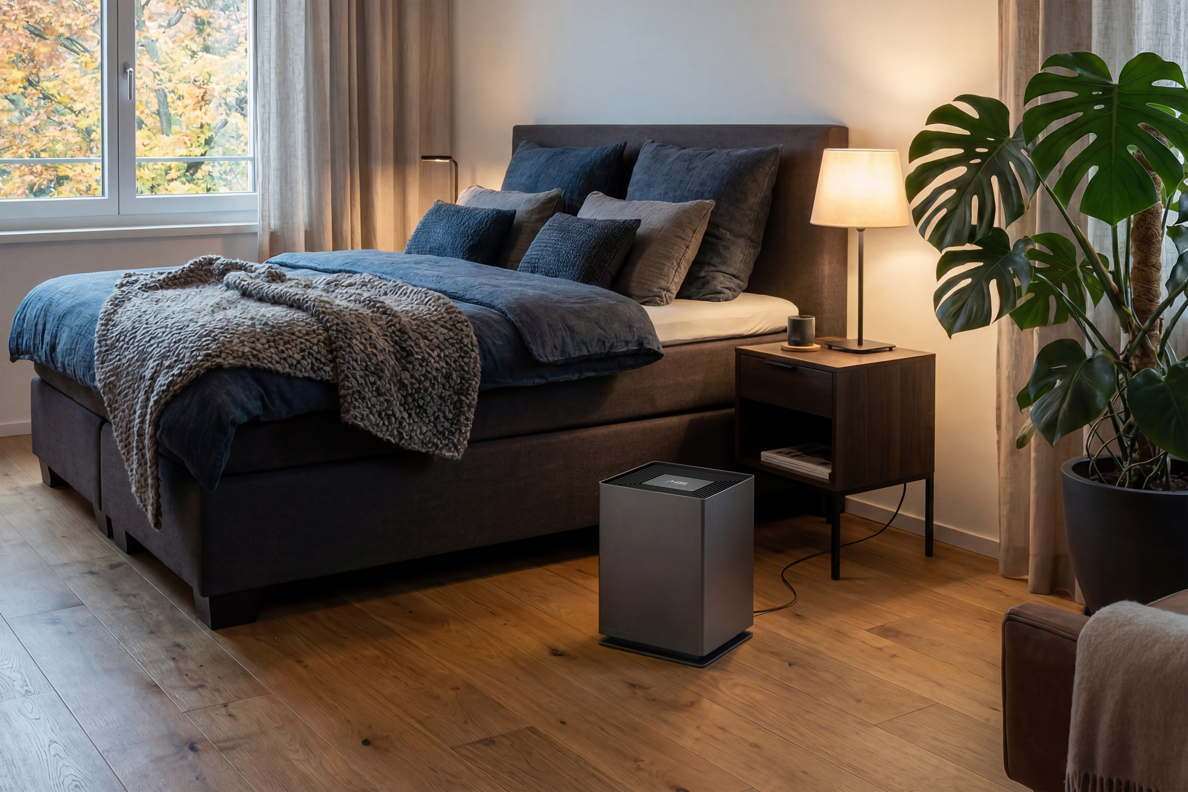 Ein modernes Schlafzimmer mit einem grauen Bett, einem Nachttisch, einer Lampe und einem Luftreiniger auf dem Holzfußboden.