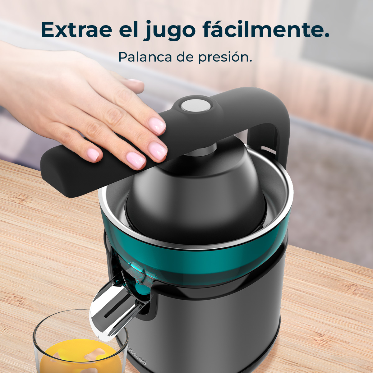 Mano presionando la palanca de un exprimidor negro y turquesa sobre mesa de madera.
