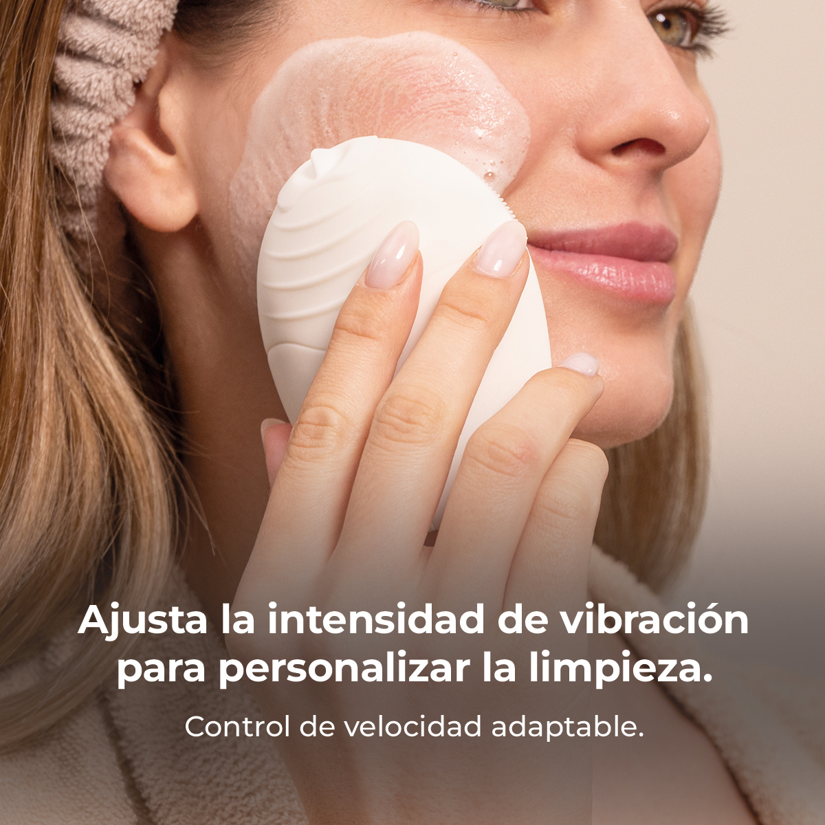 Una mujer limpia su cara con un dispositivo de limpieza electrónico blanco.