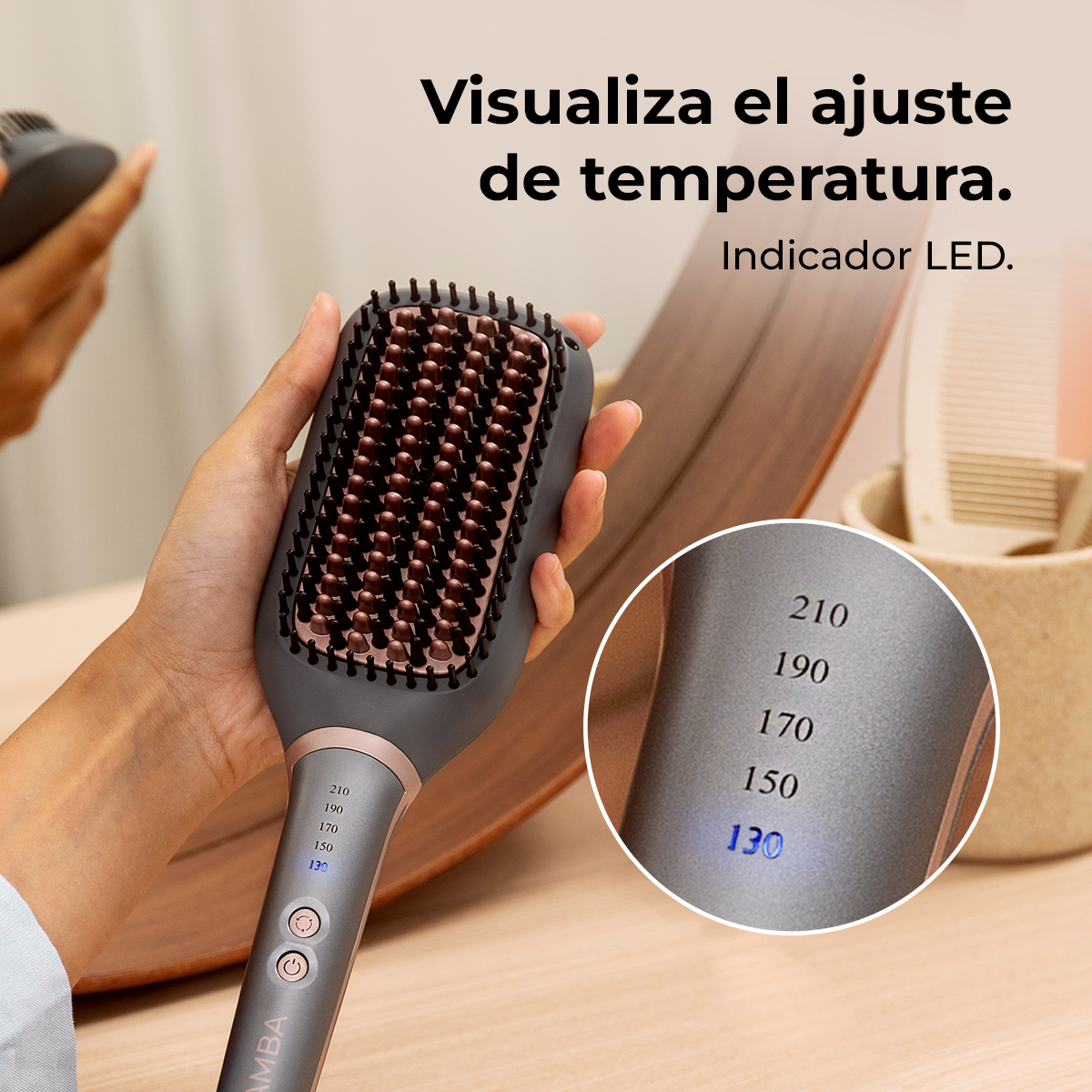 Una persona sostiene un cepillo alisador gris con cerdas marrones y pantalla LED.