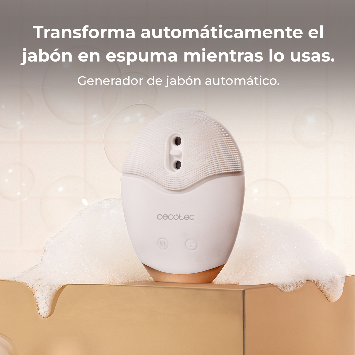 Un dispositivo de jabón automático blanco sobre una base dorada rodeado de espuma frente a una pared de azulejos.