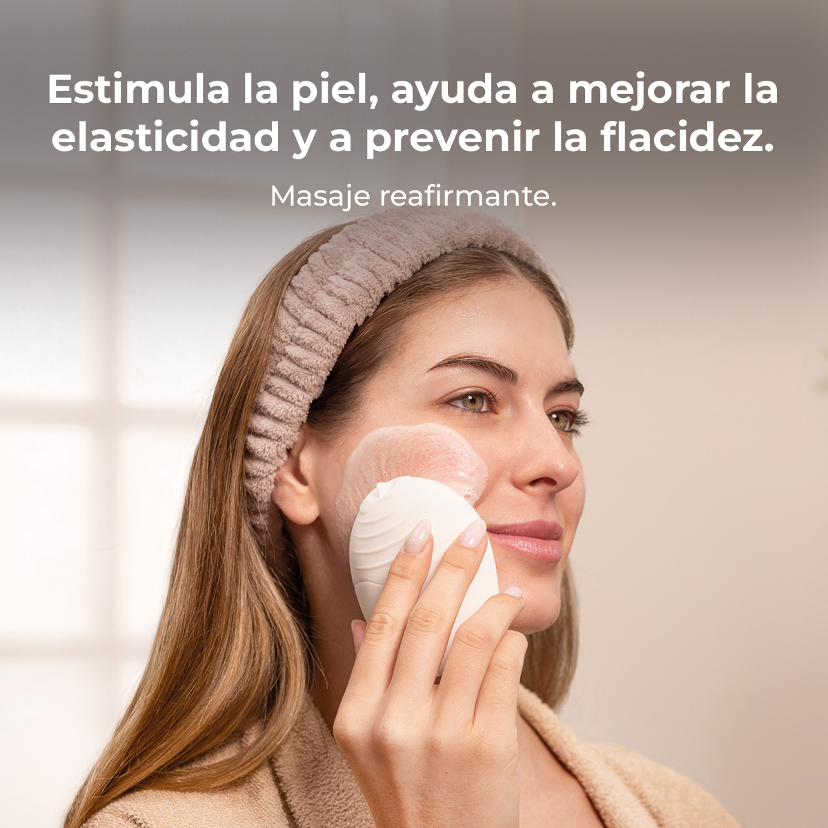 Una mujer sonriente usa un dispositivo de limpieza facial con espuma en la mejilla.