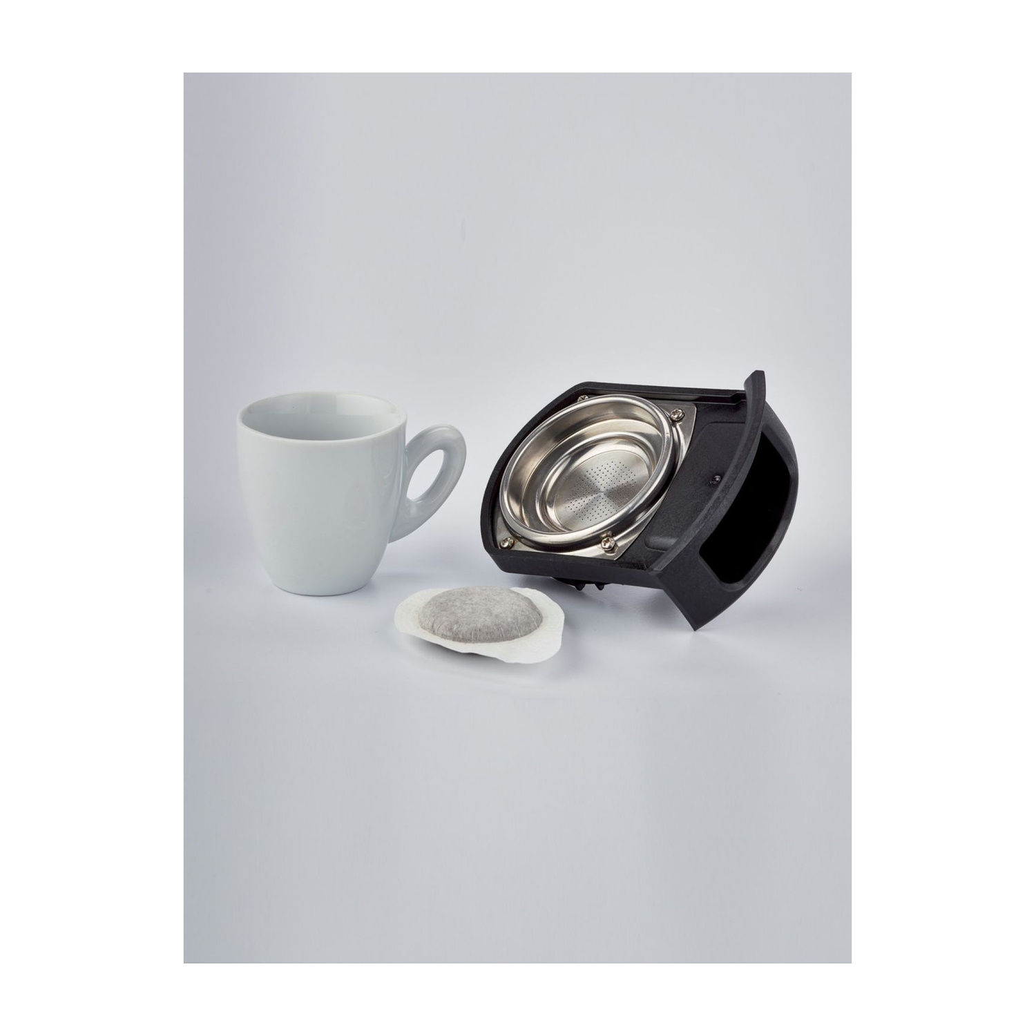 Una tazza bianca, una cialda di caffè e un portafiltro su sfondo bianco.