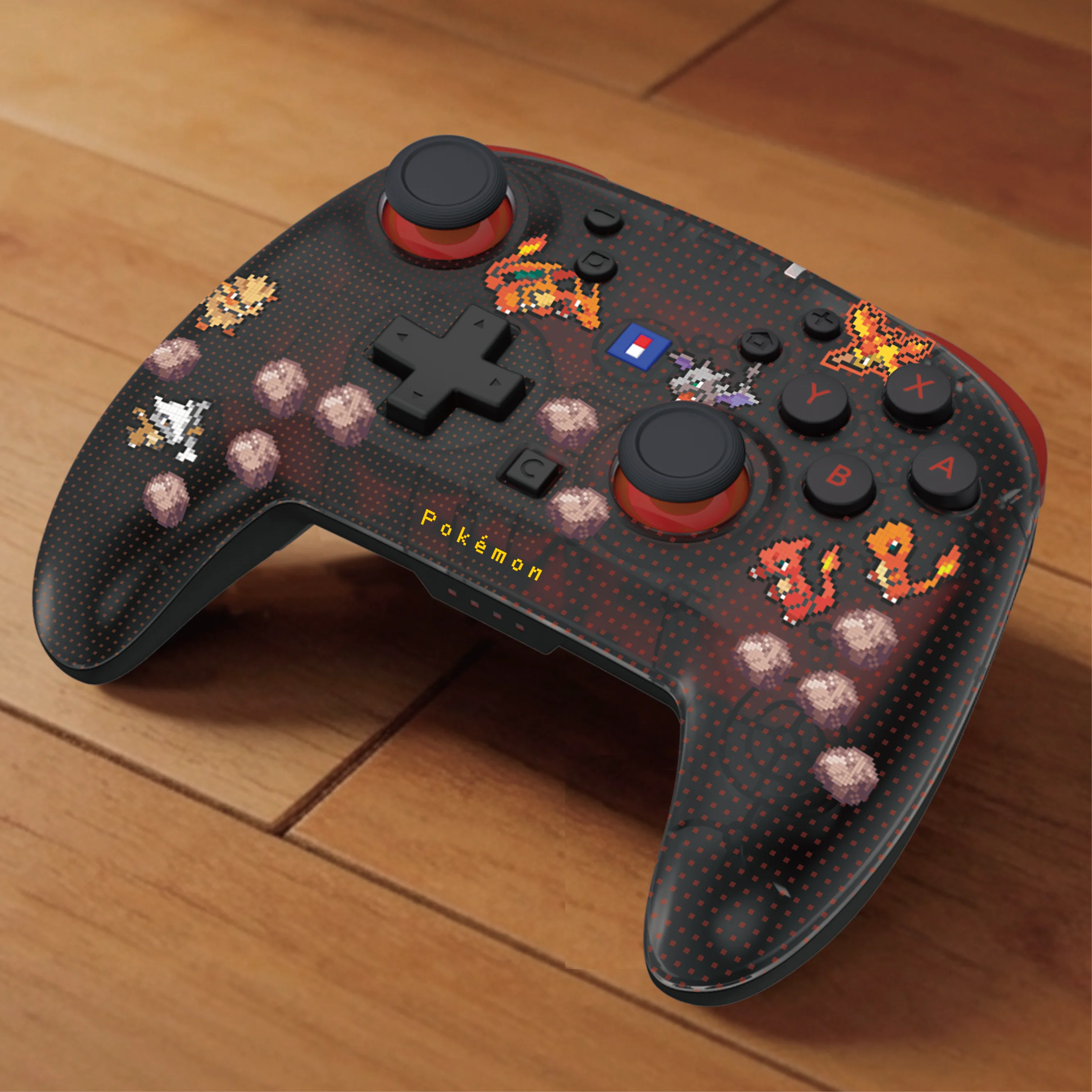 Un controller di gioco nero e rosso con grafica pixel art dei Pokémon su una superficie in legno.