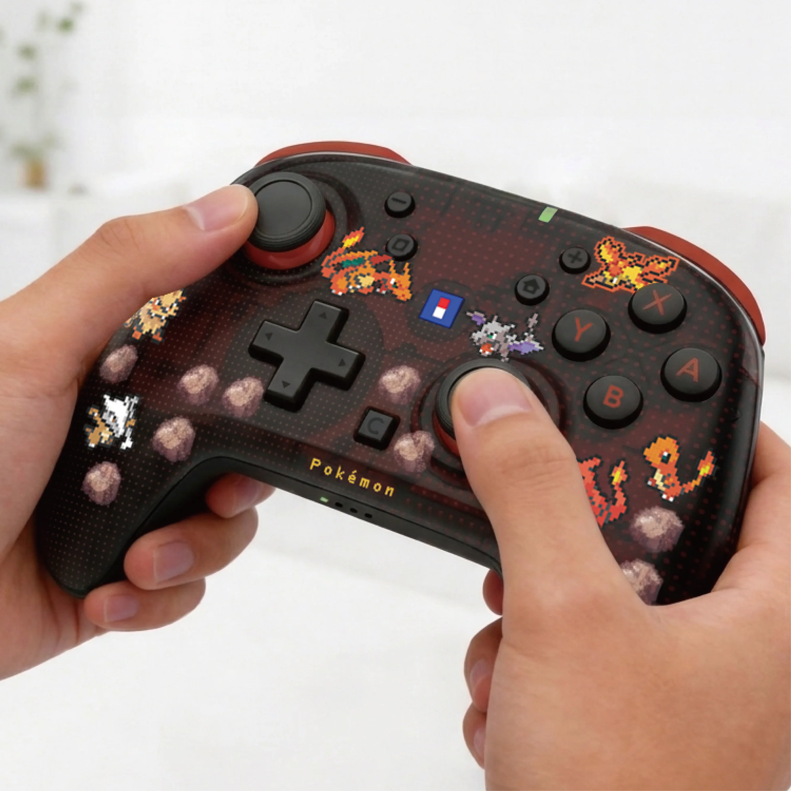 Una persona tiene in mano un controller per videogiochi a tema Pokémon scuro e traslucido.
