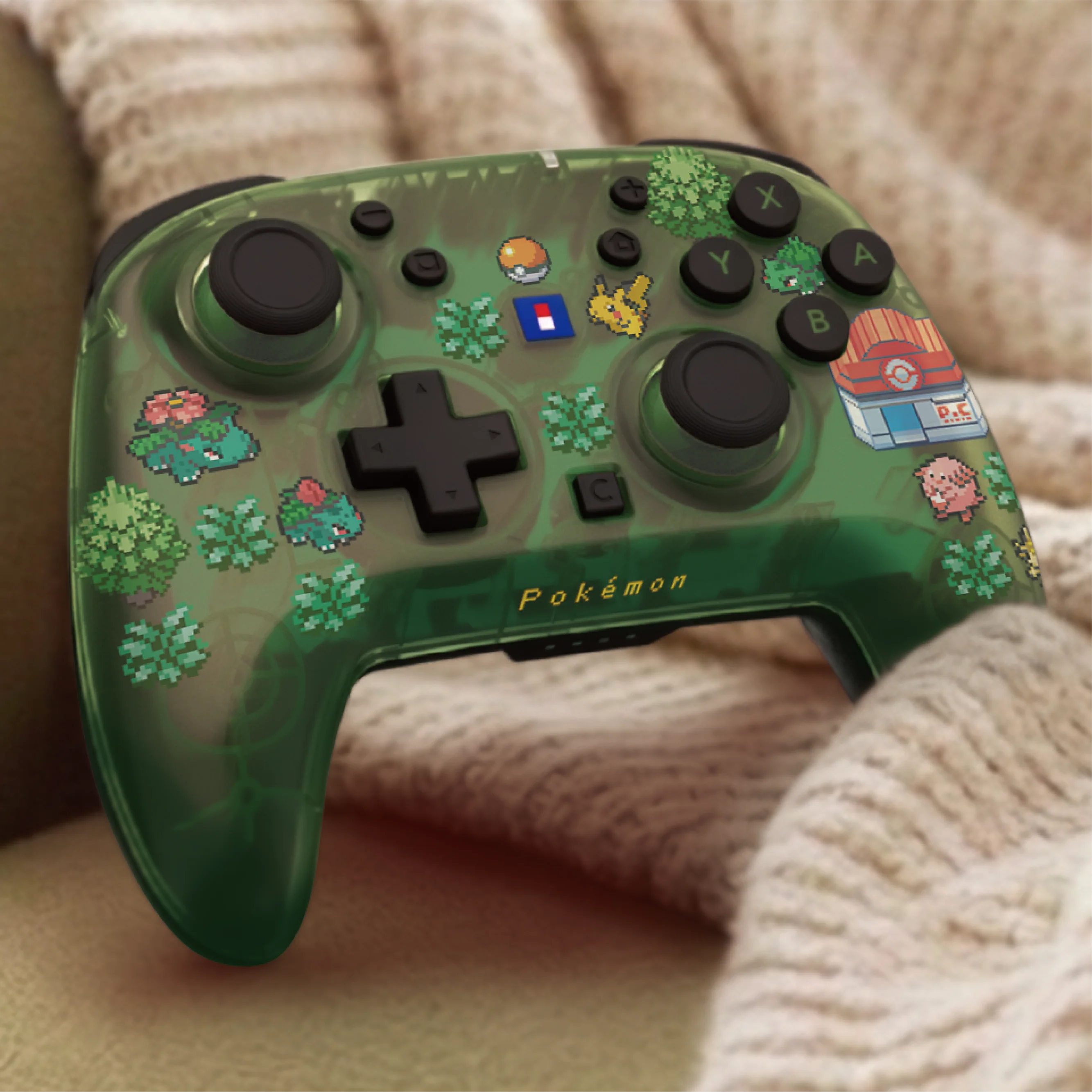 Un controller di gioco verde traslucido a tema Pokémon poggia su una coperta beige.