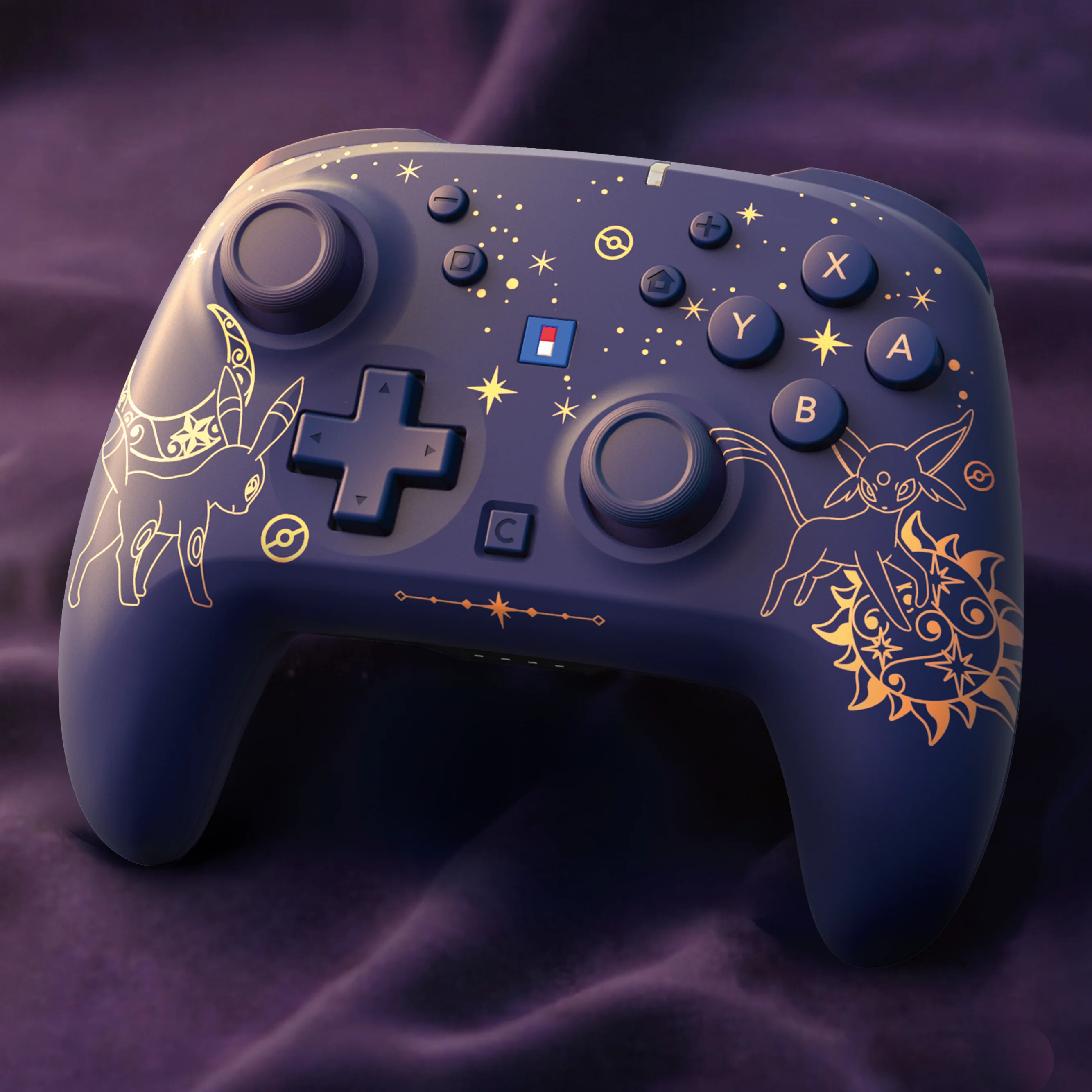 Controller di gioco blu con motivi dorati di Umbreon ed Espeon su stoffa scura.