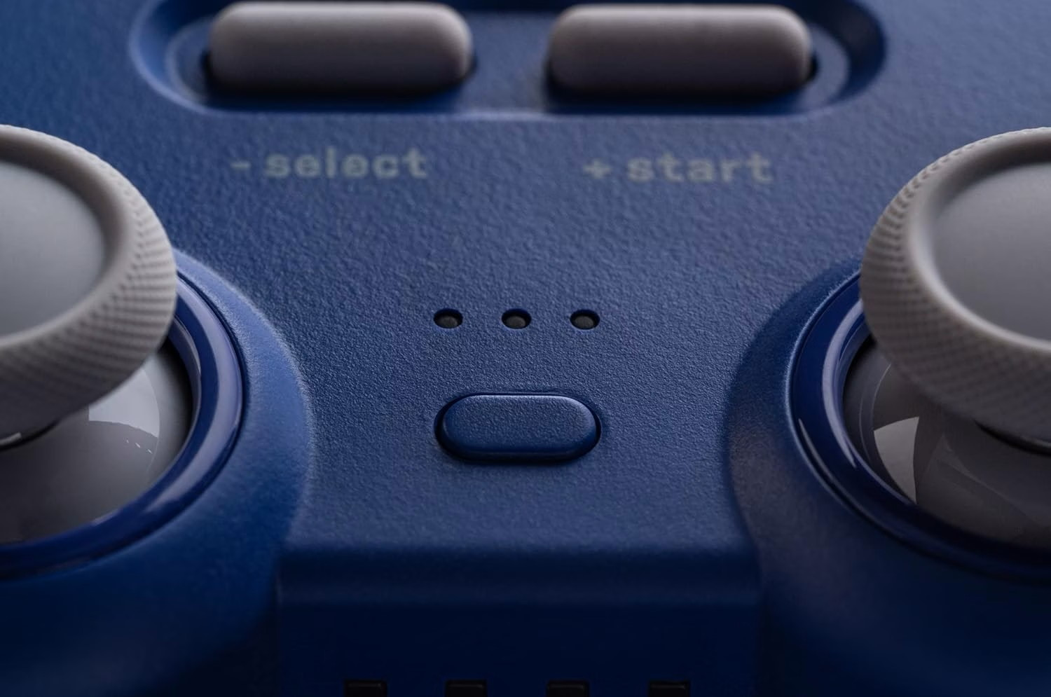 Controller di gioco blu con due joystick grigi, pulsanti select e start e spie luminose.