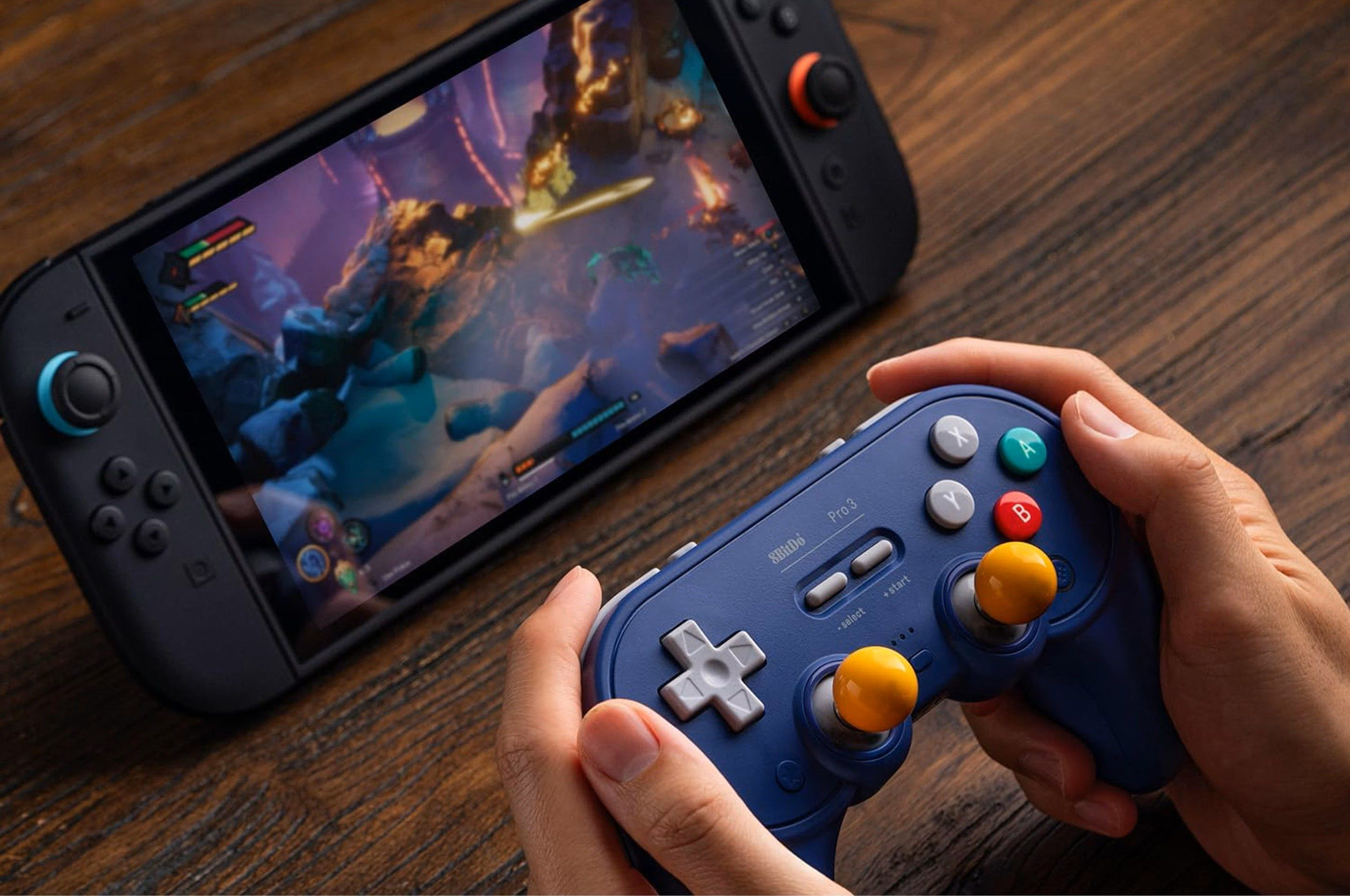 Mani che tengono un controller blu con levette gialle e una console di gioco sullo sfondo.