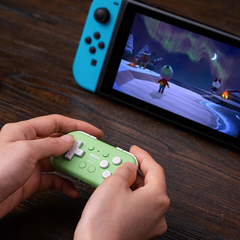 Qualcuno gioca ad Animal Crossing su una Nintendo Switch tenendo un piccolo controller verde.