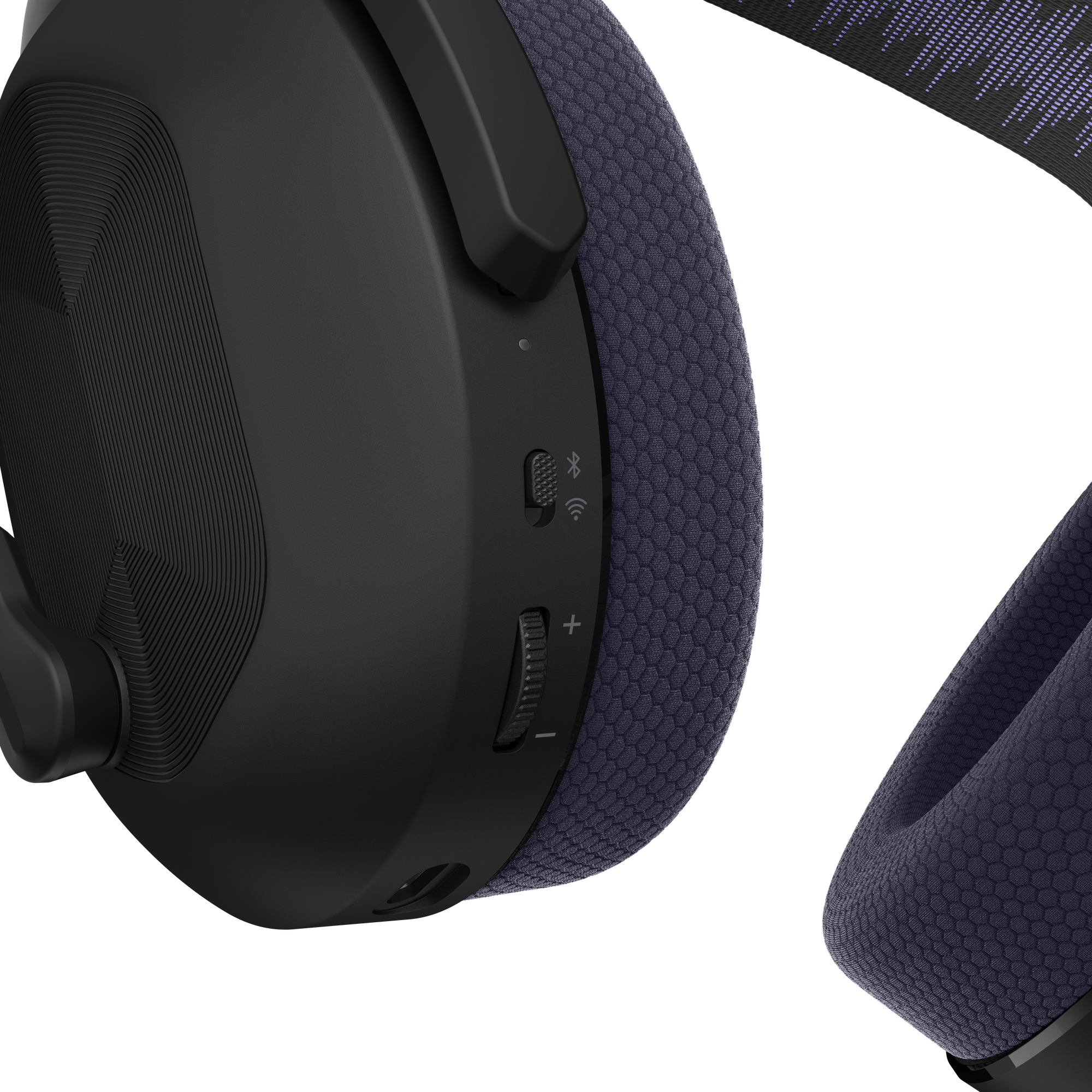 Primer plano de auriculares negros con almohadillas de malla morada, botones de control y rueda de volumen.