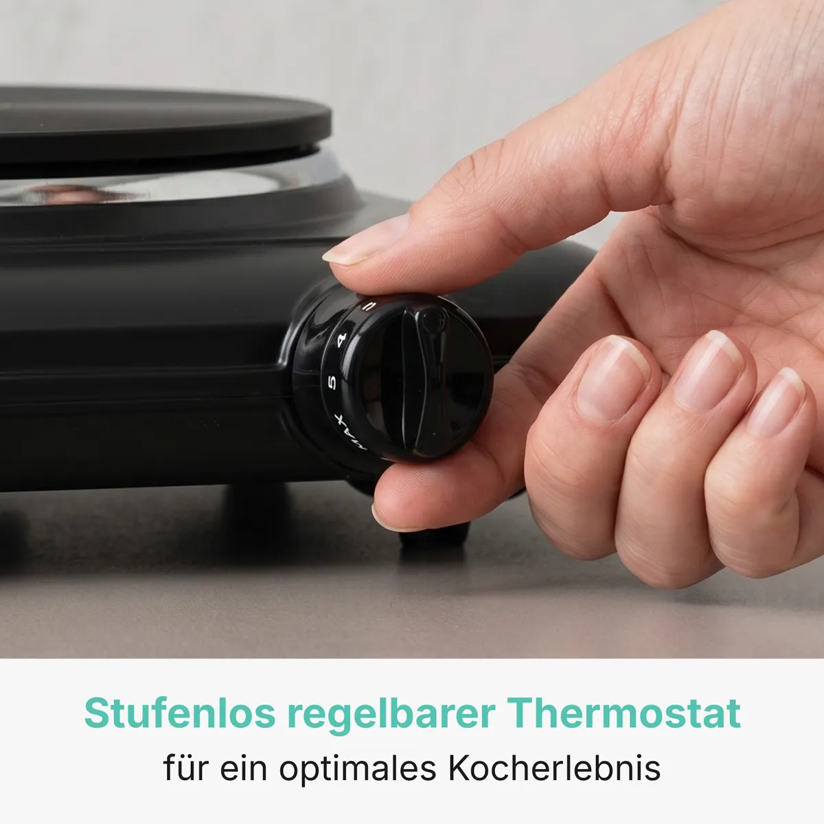 Eine Hand dreht den schwarzen Temperaturregler einer kleinen elektrischen Kochplatte.