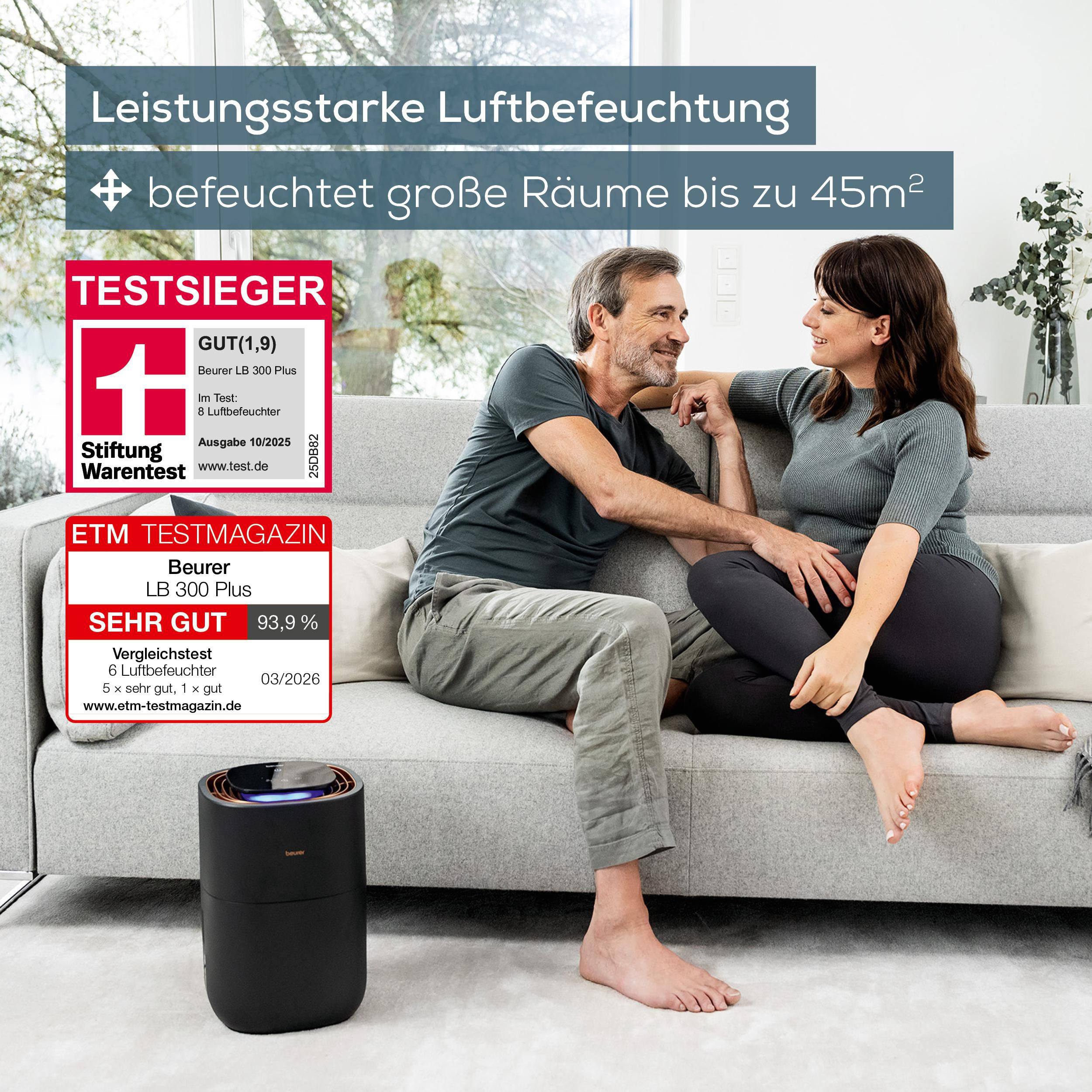Paar sitzt auf Sofa im hellen Wohnzimmer mit Luftbefeuchter im Vordergrund und Testergebnissen.