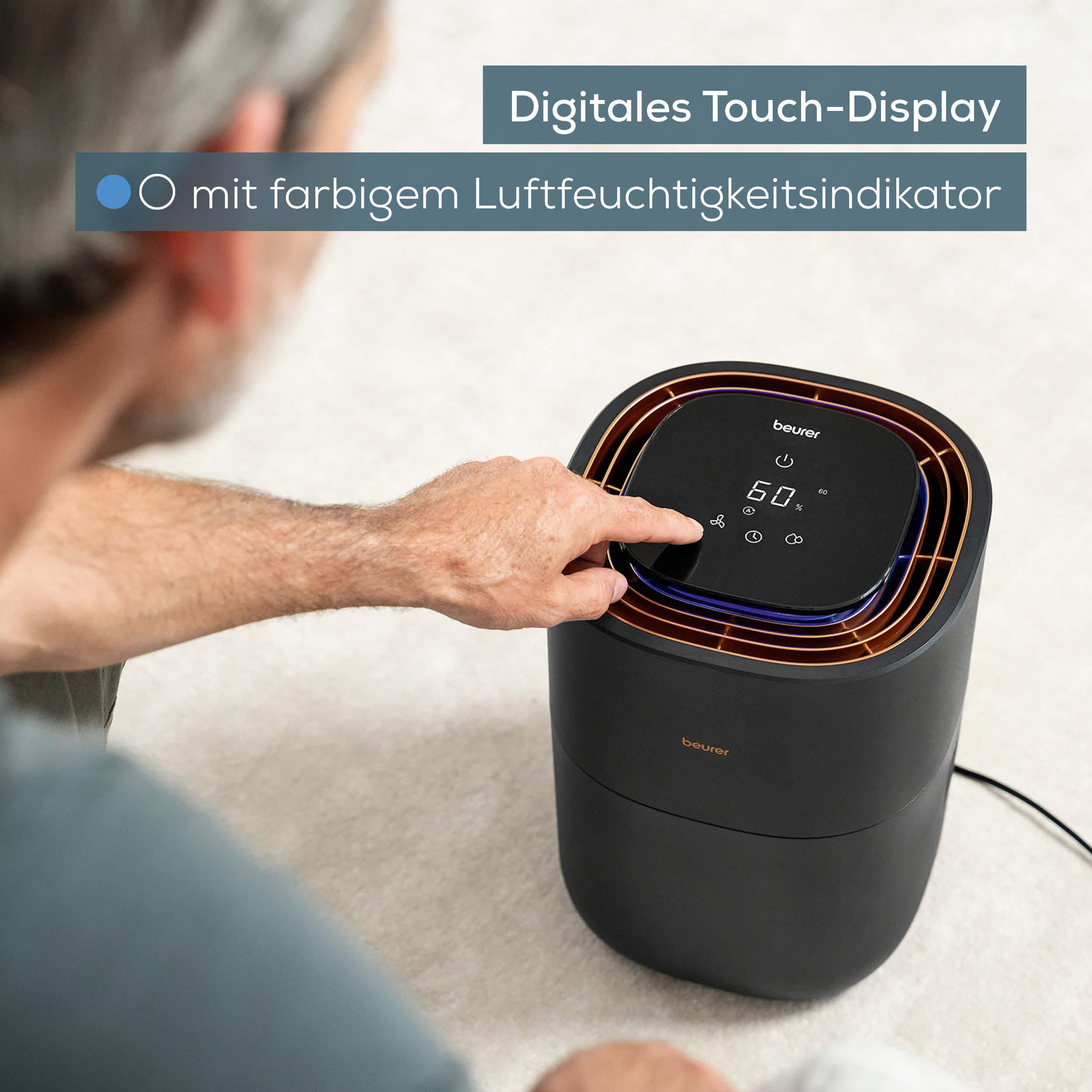 Ein Mann bedient das digitale Touch-Display eines schwarzen Beurer Luftbefeuchters.
