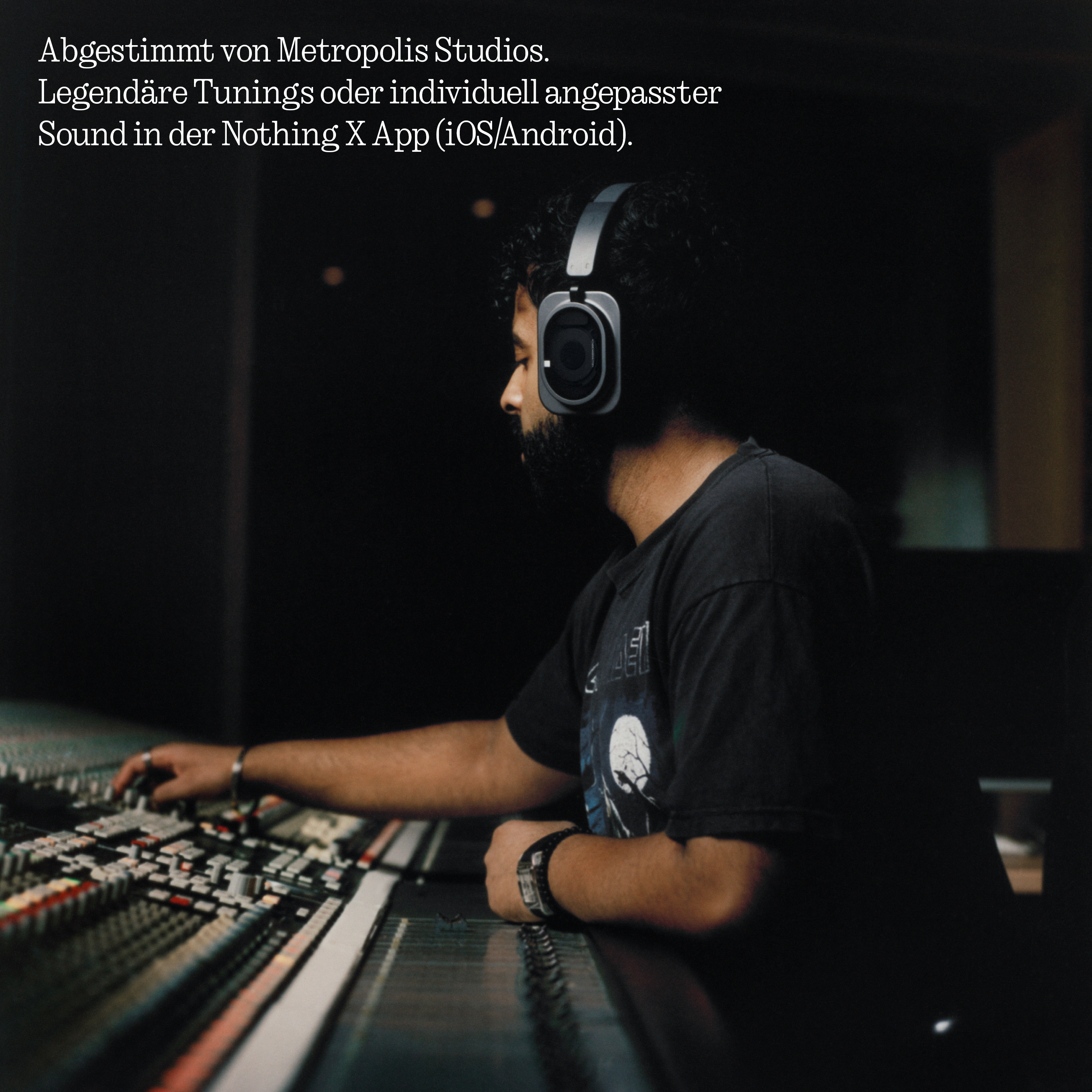 Ein Mann mit Kopfhörern sitzt in einem dunklen Studio vor einem großen Mischpult und bedient die Regler.