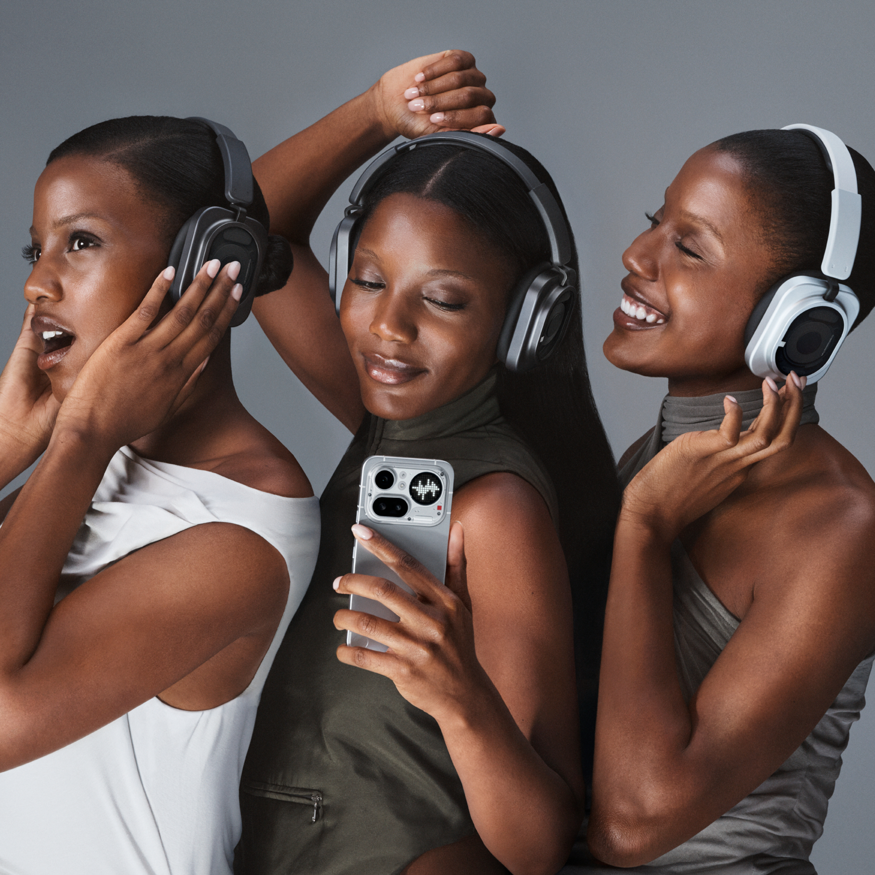 Drei schwarze Frauen mit Kopfhörern genießen Musik; die mittlere hält ein Smartphone.