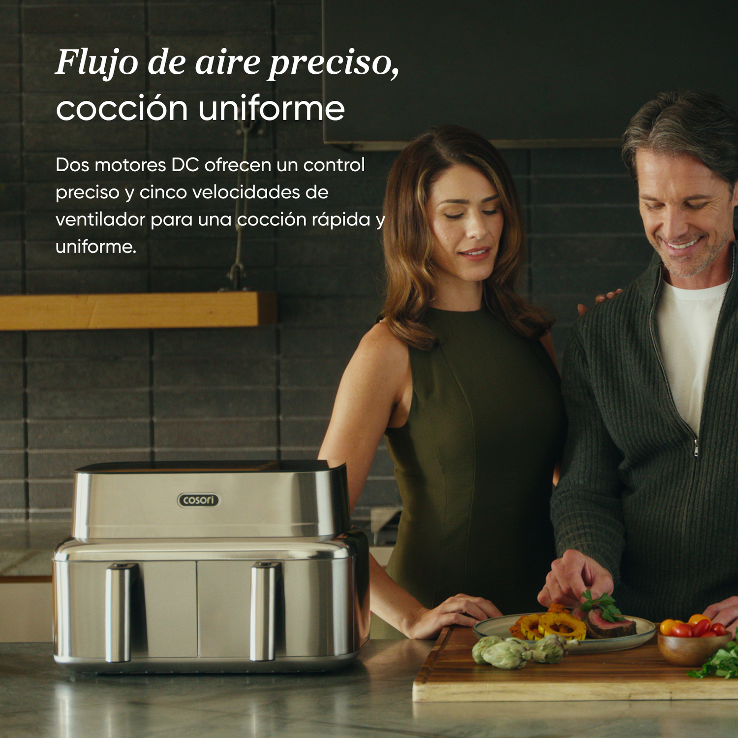 Un hombre y una mujer en una cocina con una freidora de aire Cosori de acero inoxidable.