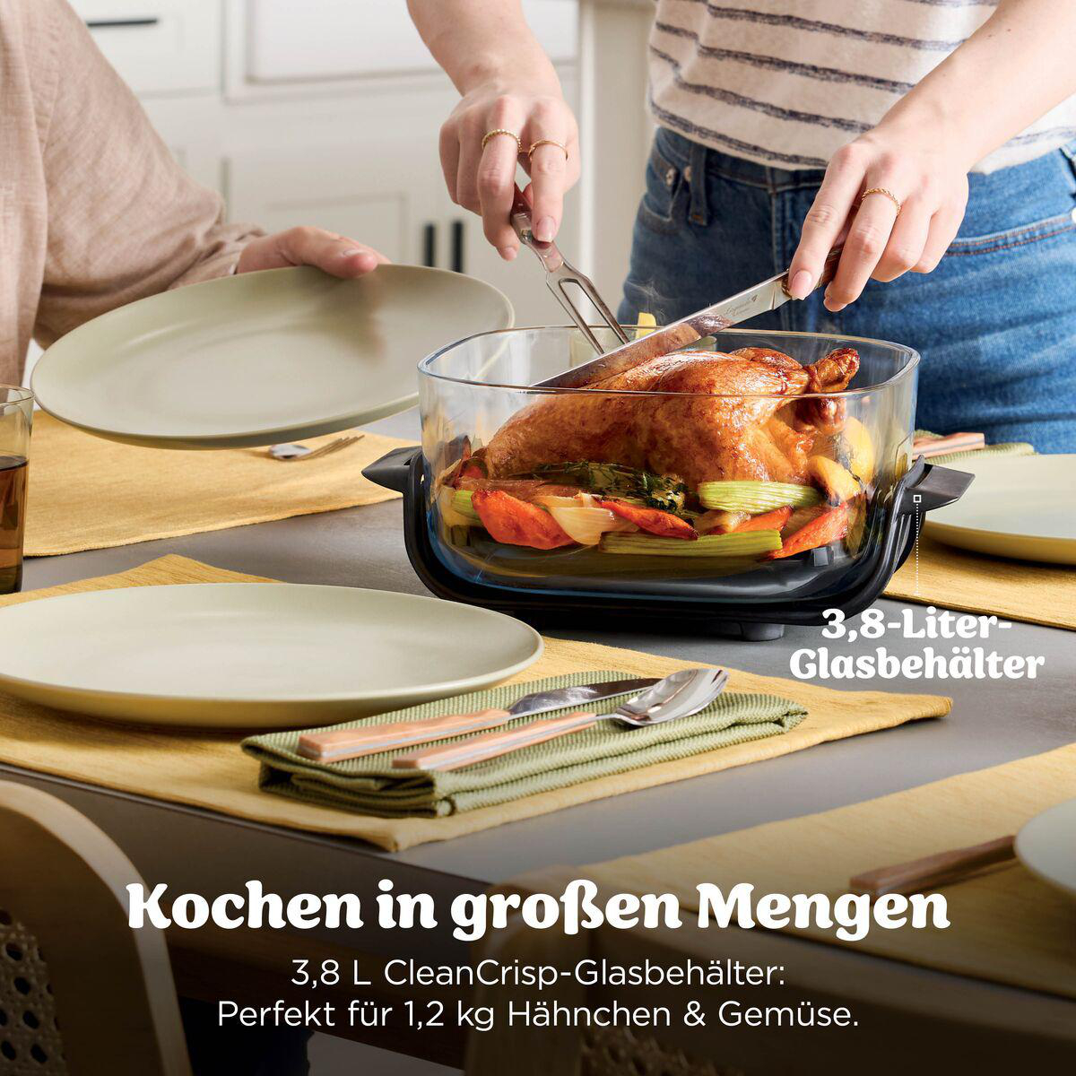 Eine Person schneidet ein ganzes Hähnchen mit Gemüse in einer 3,8-Liter-Glasschüssel auf einem Tisch.