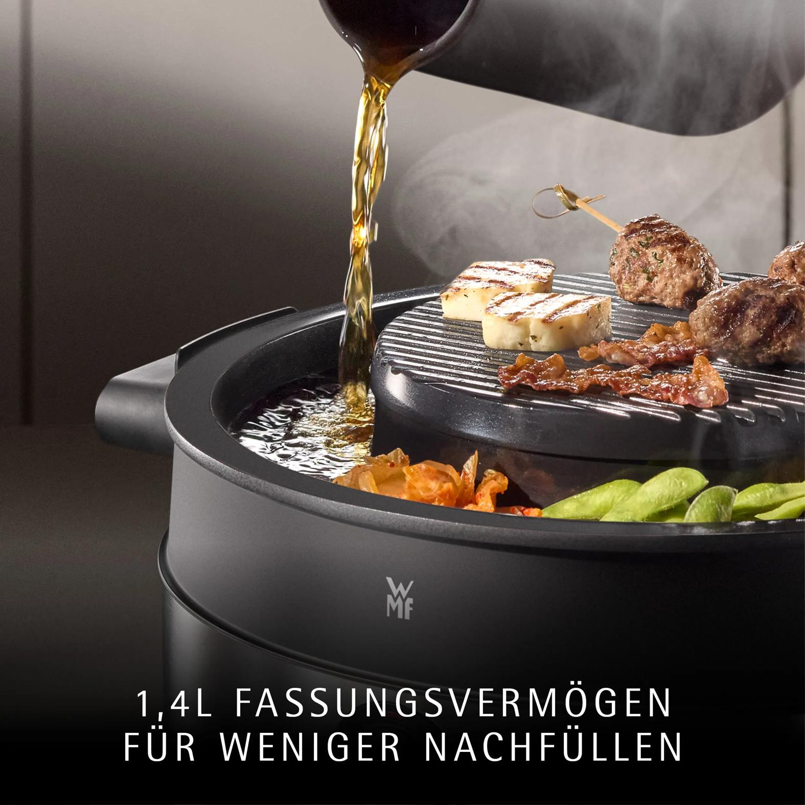 Flüssigkeit wird in einen schwarzen Tischgrill mit Fleisch und Gemüse gegossen.