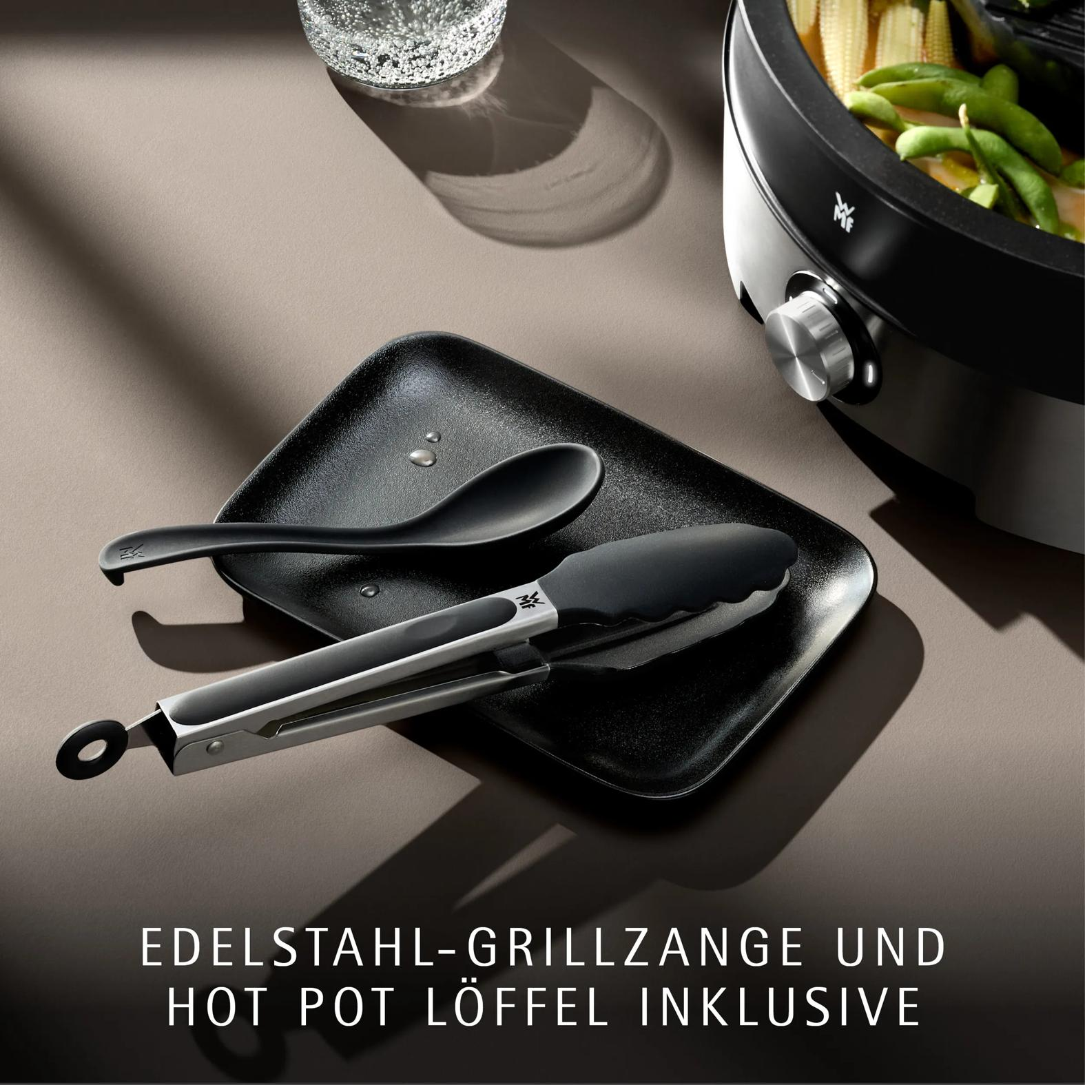 Edelstahl-Grillzange und Hot-Pot-Löffel auf schwarzem Tablett neben Hot Pot.