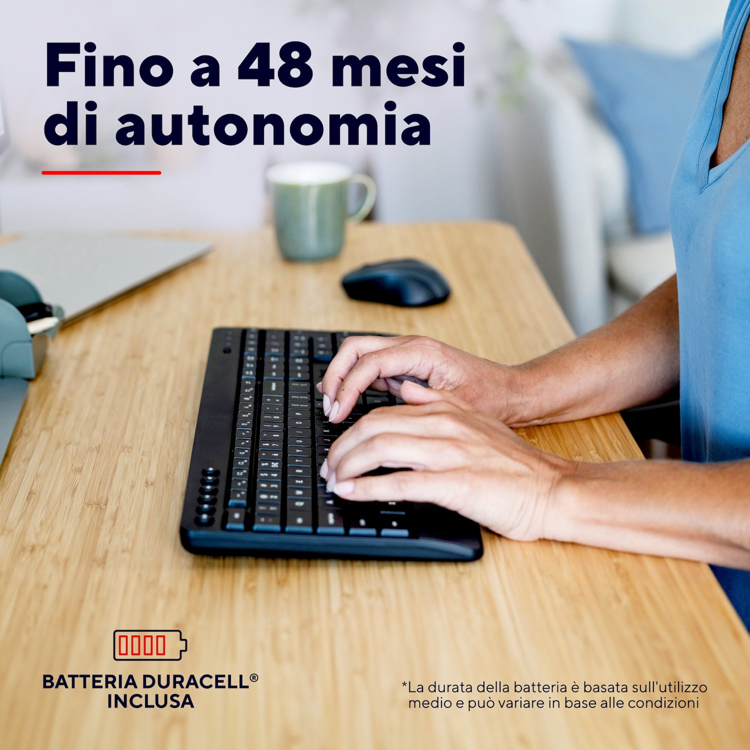 Persona che digita su una tastiera nera su una scrivania in legno, con tazza e mouse.