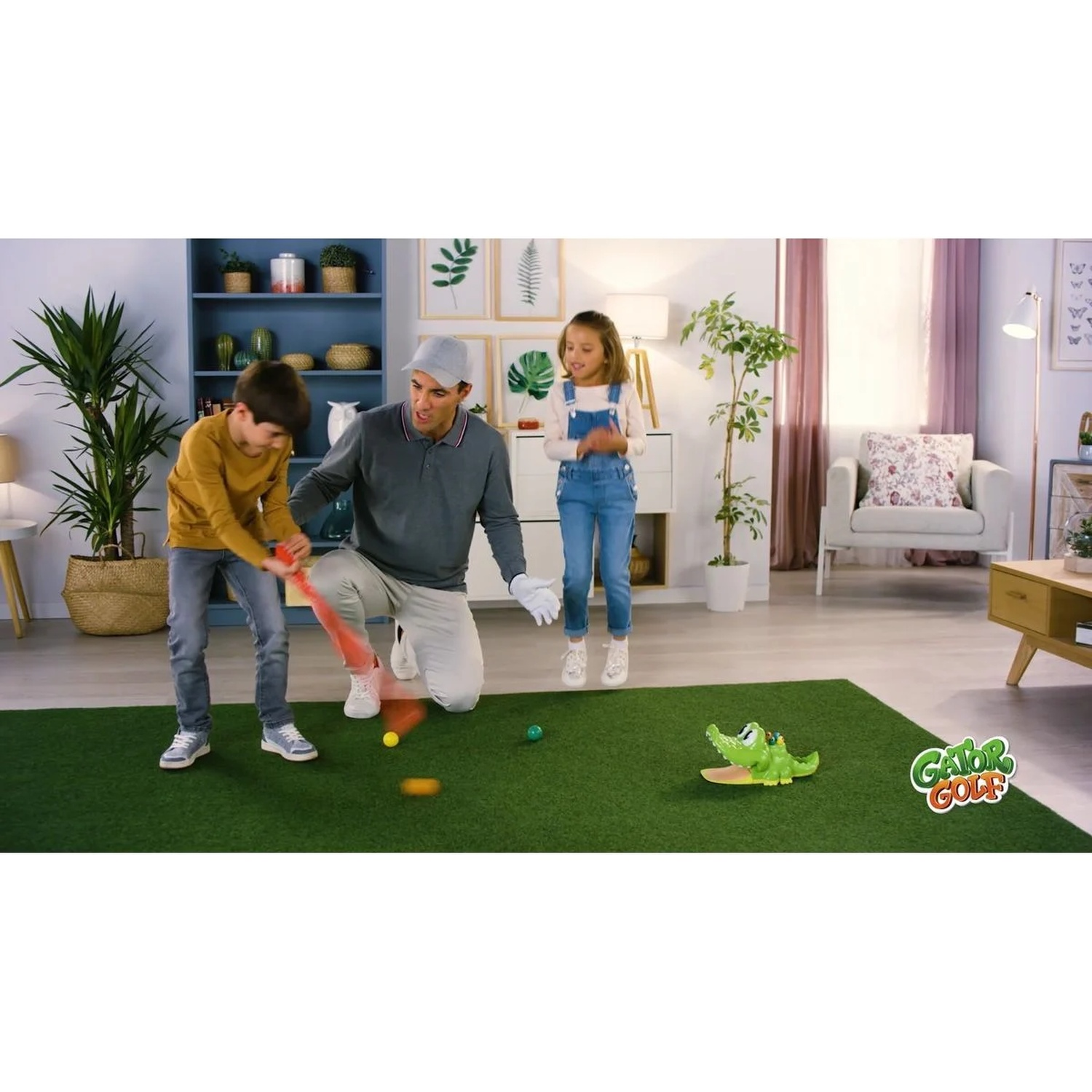 Un homme et deux enfants jouent au Gator Golf sur un tapis vert dans le salon.
