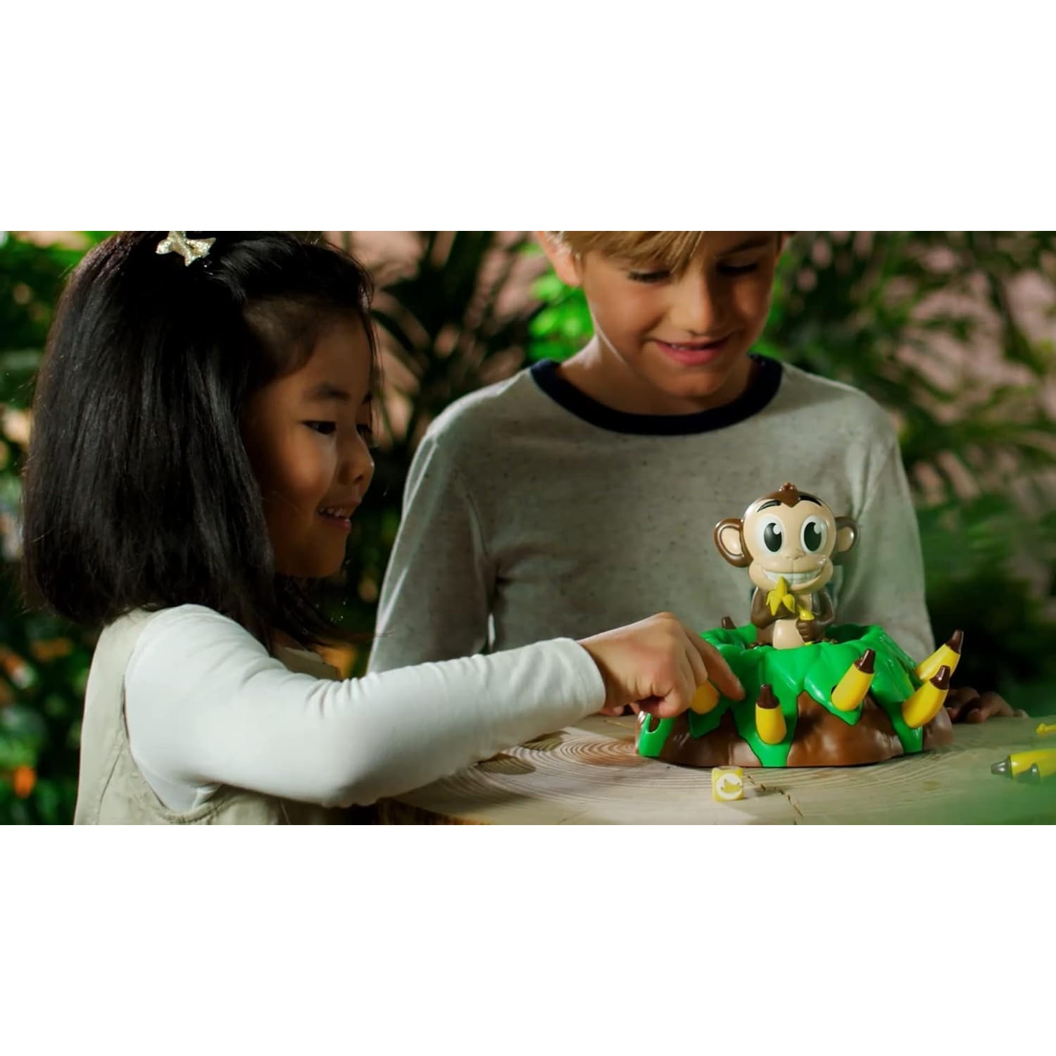 Un garçon et une fille jouent joyeusement à un jeu de singe sur une table en bois.