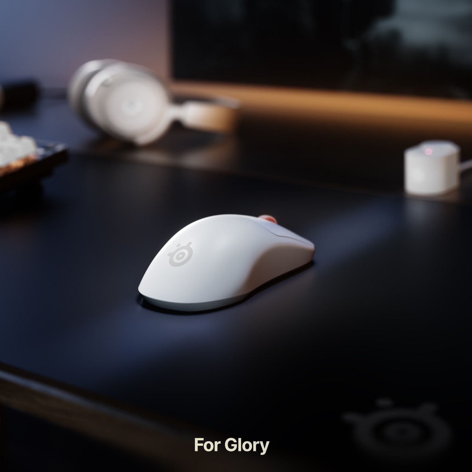 Een witte gamingmuis op een zwart bureau, met witte koptelefoon en accessoires op de achtergrond.