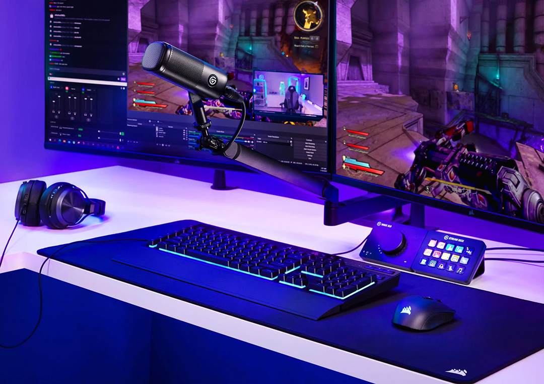 Játékos asztali beállítás két monitorral, mechanikus billentyűzettel, egérrel, fejhallgatóval, mikrofonnal és stream deckkel.