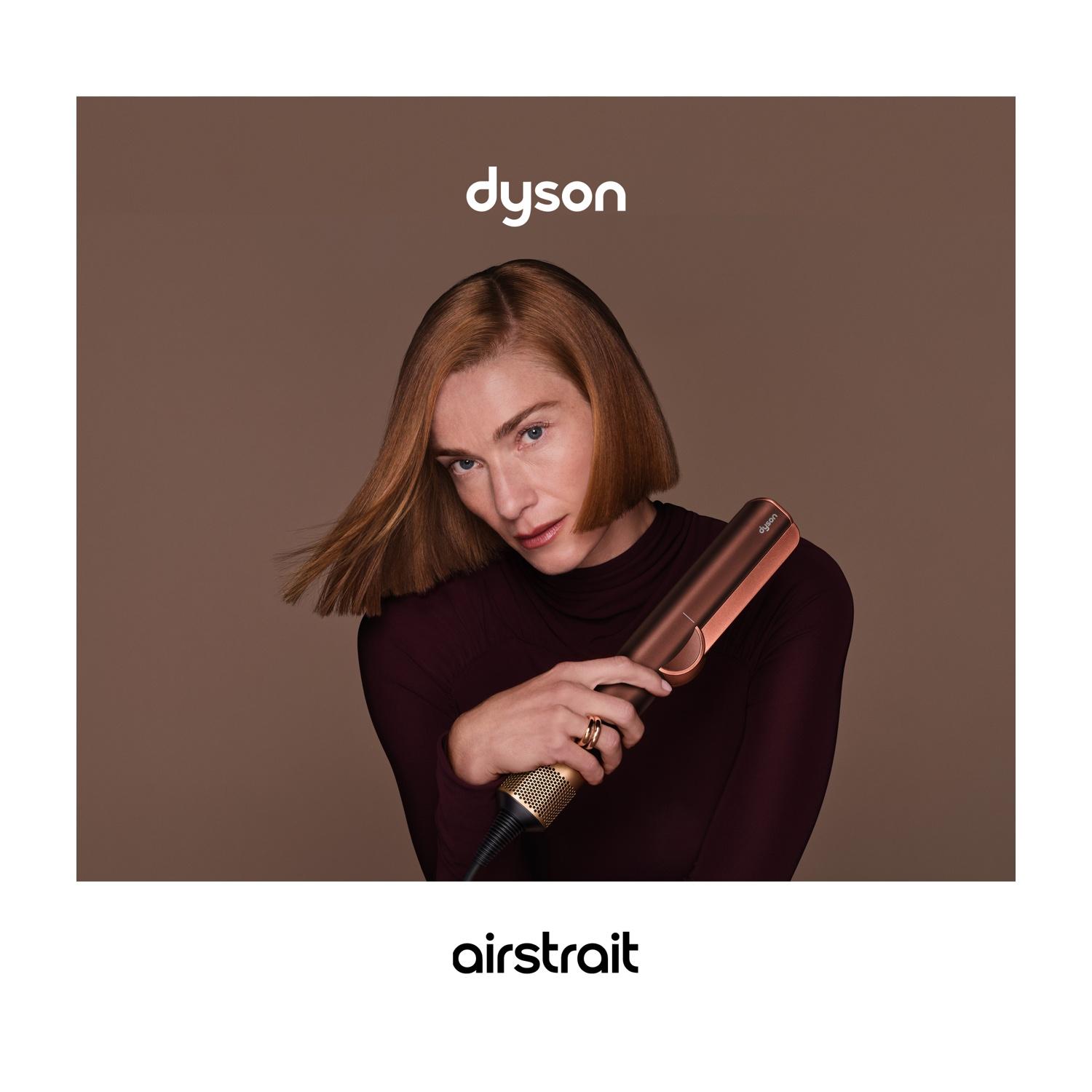 Donna tiene una piastra Dyson Airstrait su sfondo marrone, logo Dyson in alto.
