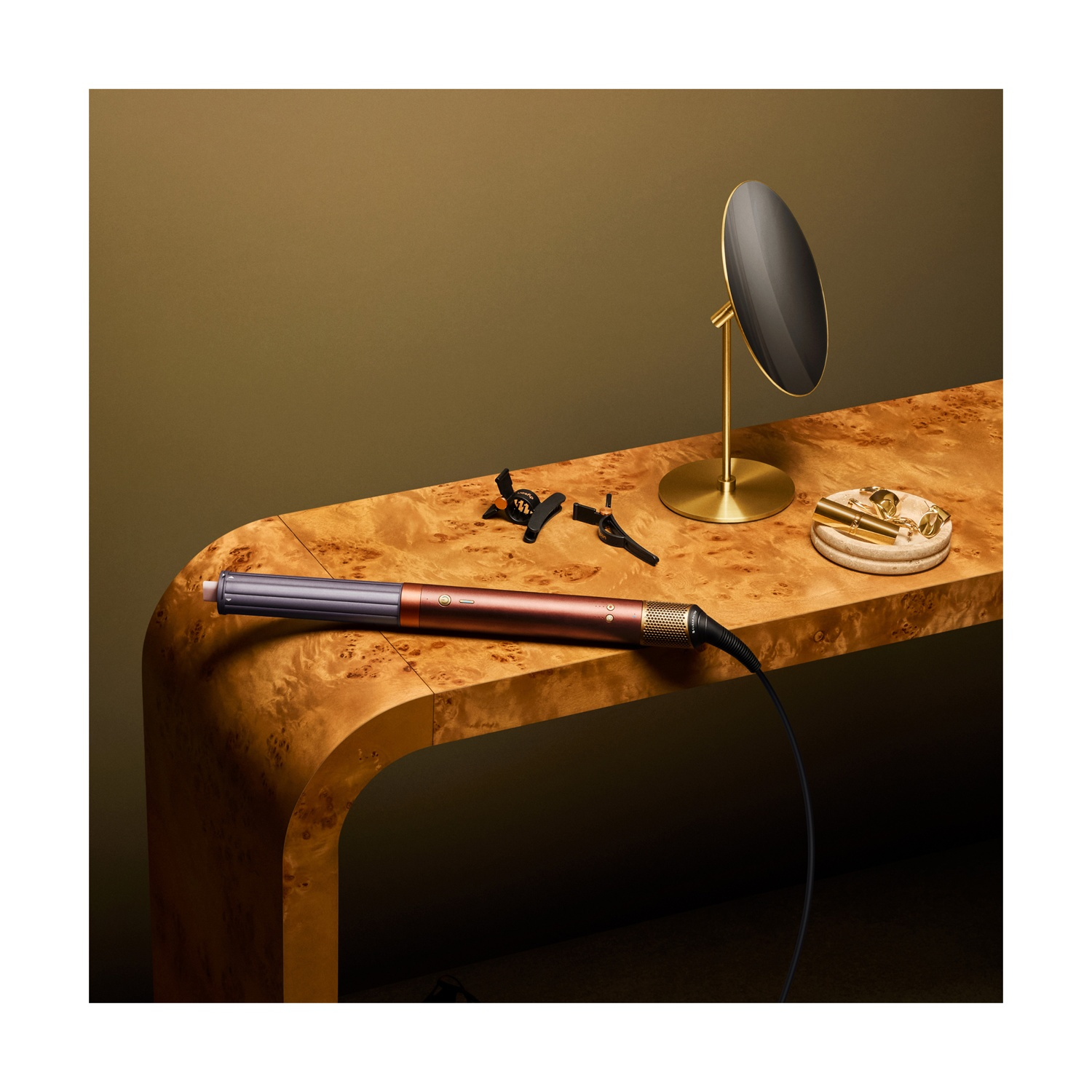 Uno strumento per lo styling dei capelli arancione è su un tavolo di legno con specchio e clip in una stanza calda.