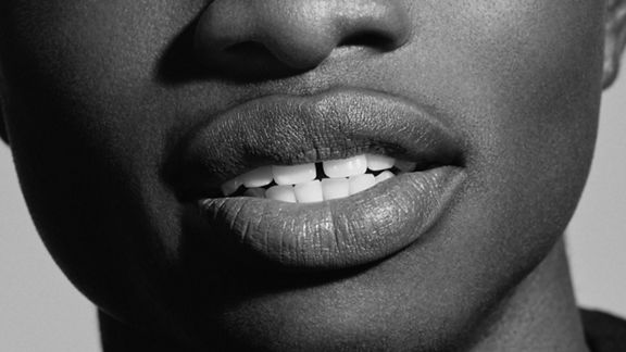 Gros plan de lèvres foncées et de dents blanches en noir et blanc.