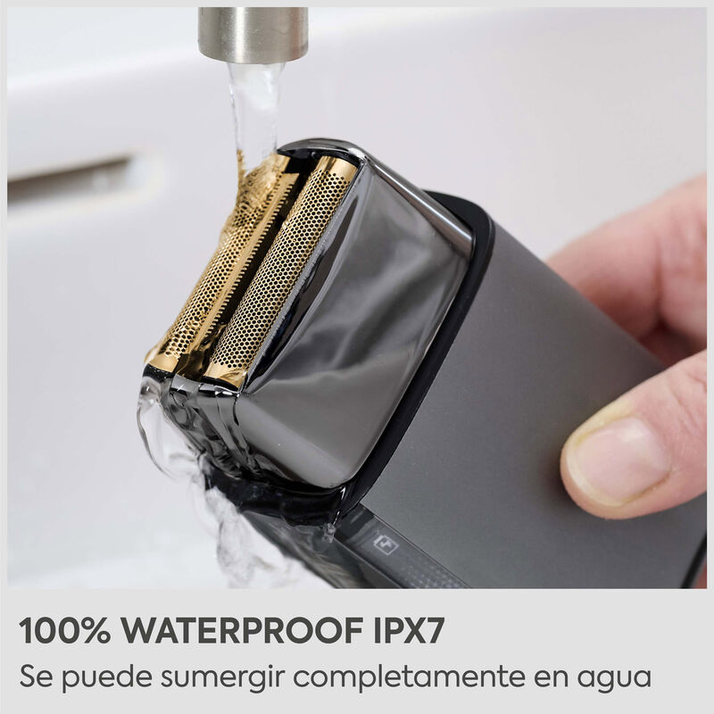 Una afeitadora eléctrica se enjuaga bajo el agua, con texto abajo que dice '100% impermeable IPX7'.