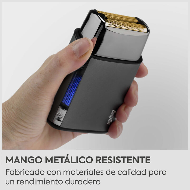 Mano sosteniendo una afeitadora eléctrica negra con cuchillas doradas.