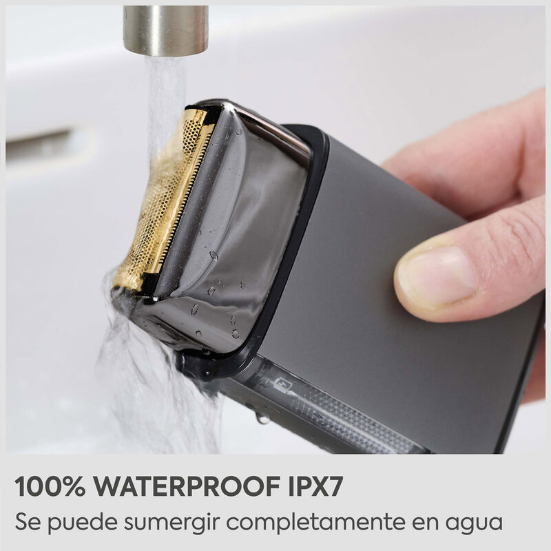 Una afeitadora eléctrica se limpia bajo el agua corriente en un lavabo.