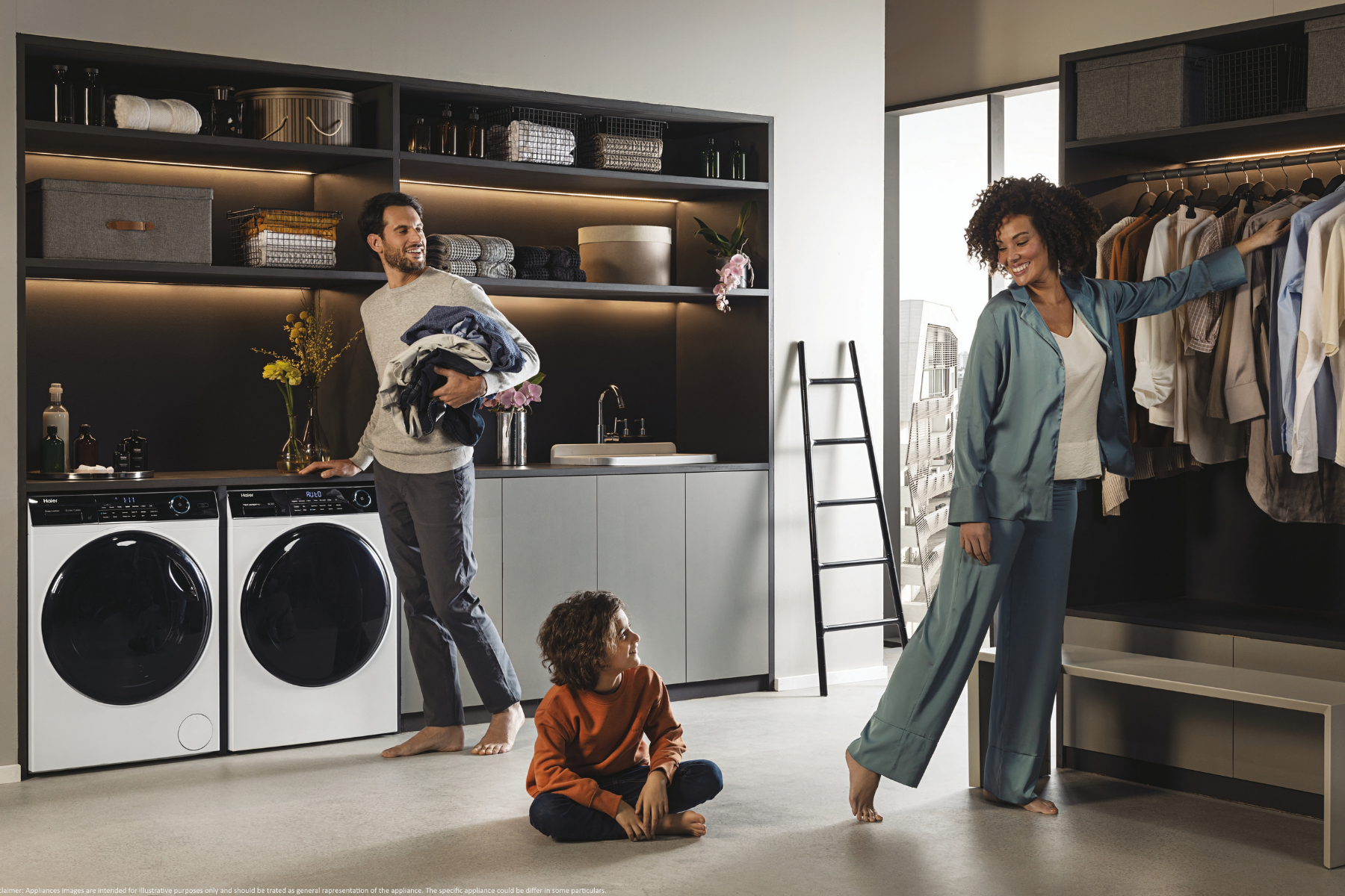 Una familia en un hogar moderno; el padre sostiene ropa, el hijo está sentado en el suelo, la madre elige ropa.