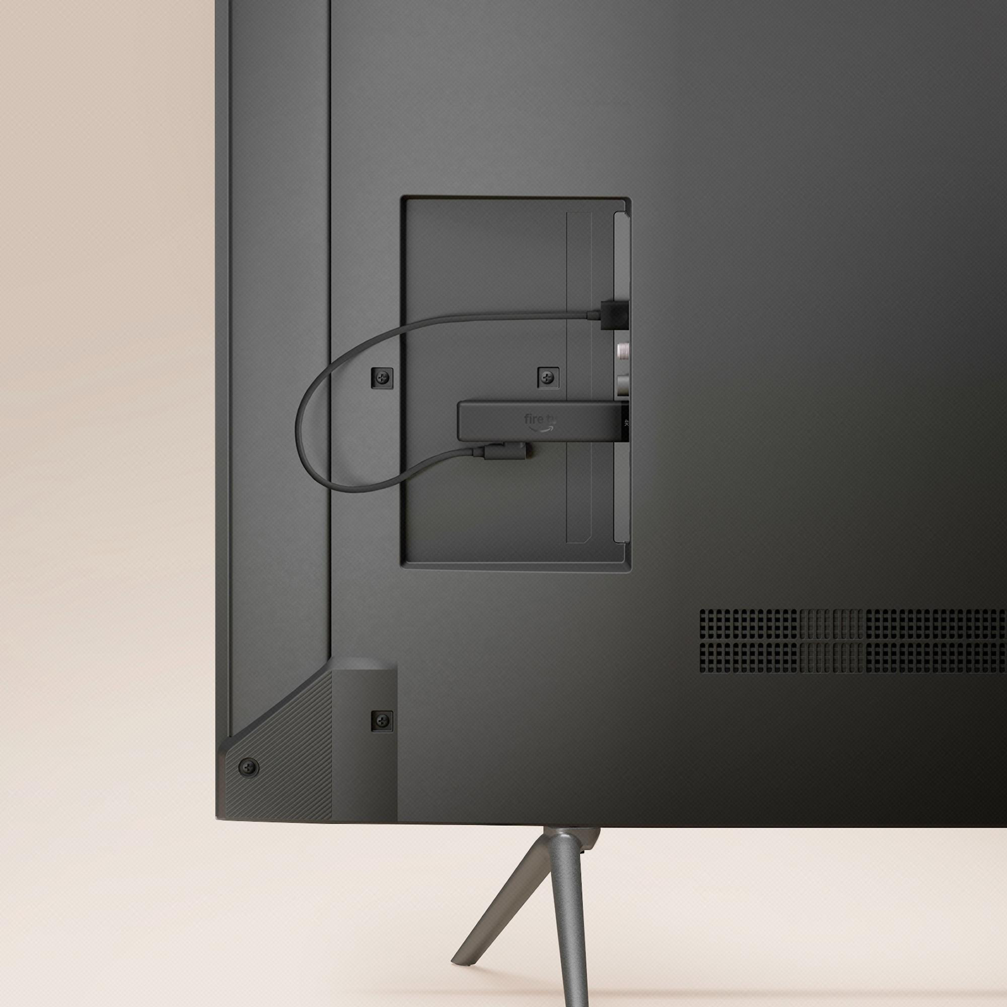 Ein schwarzer Amazon Fire TV Stick eingesteckt in den Rückwandanschluss eines dunklen Fernsehers.