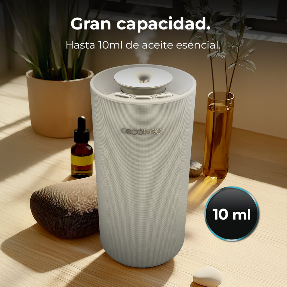 Un difusor de aroma blanco con vapor en una mesa de madera, rodeado de plantas y frascos de aceite.