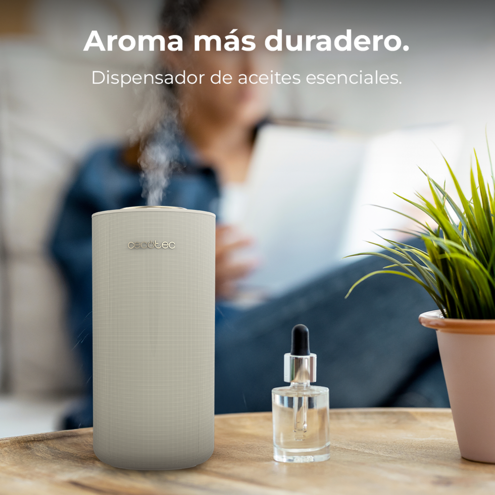 Un difusor que emite vapor está sobre una mesa de madera junto a un frasco de aceite y una planta.